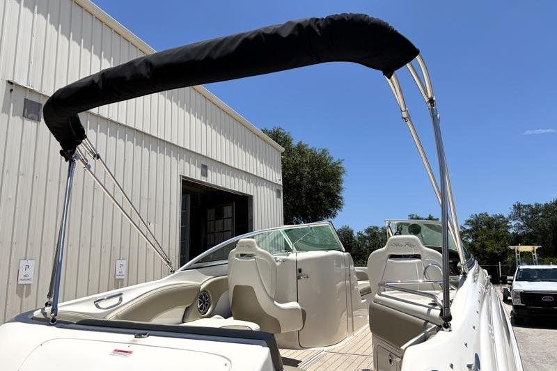 2007 Sea Ray 240 Sundeck boat with bimini top, parked near a warehouse.