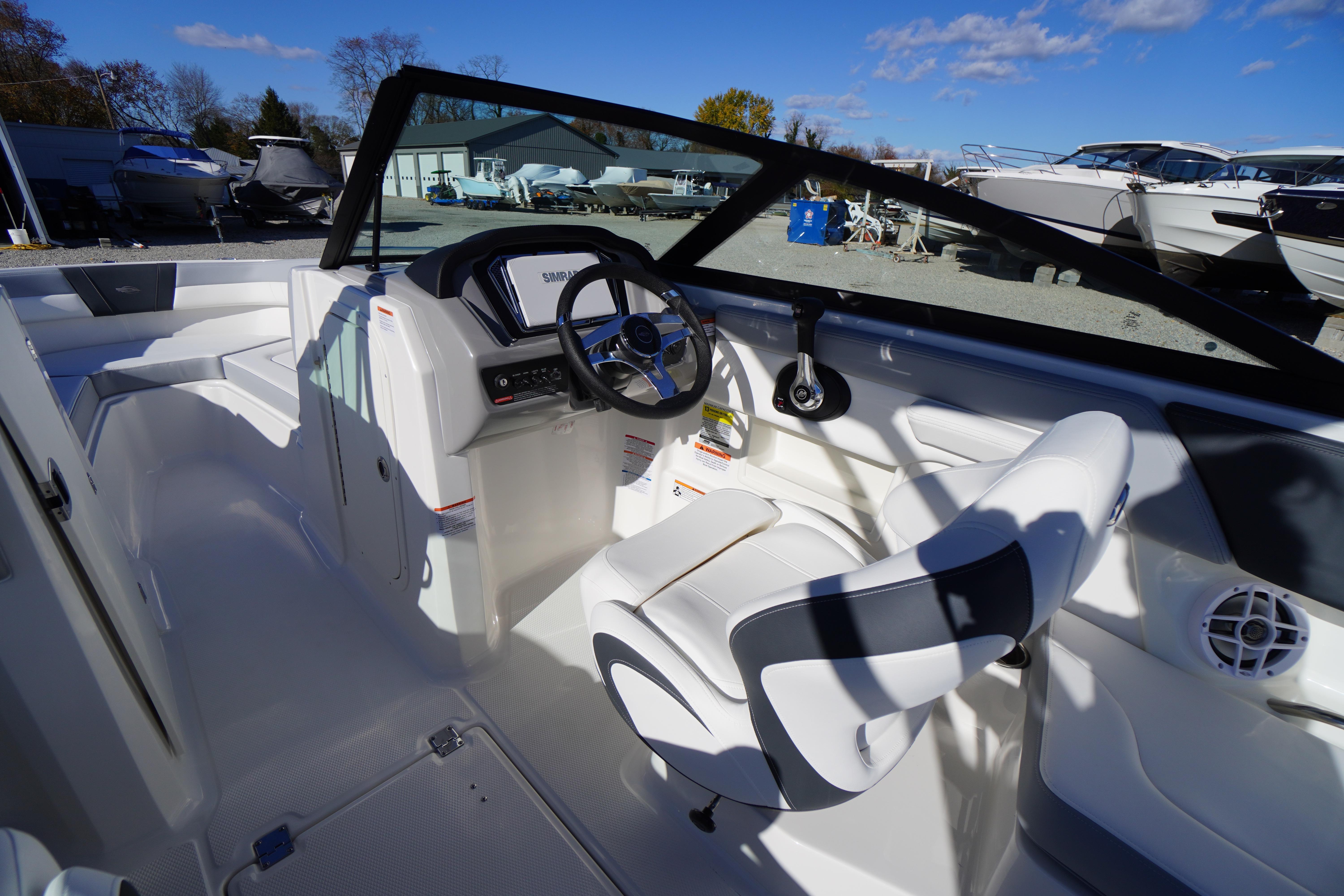 2026 Chaparral 23 SSi boat interior with steering wheel and seating, docked outdoors.