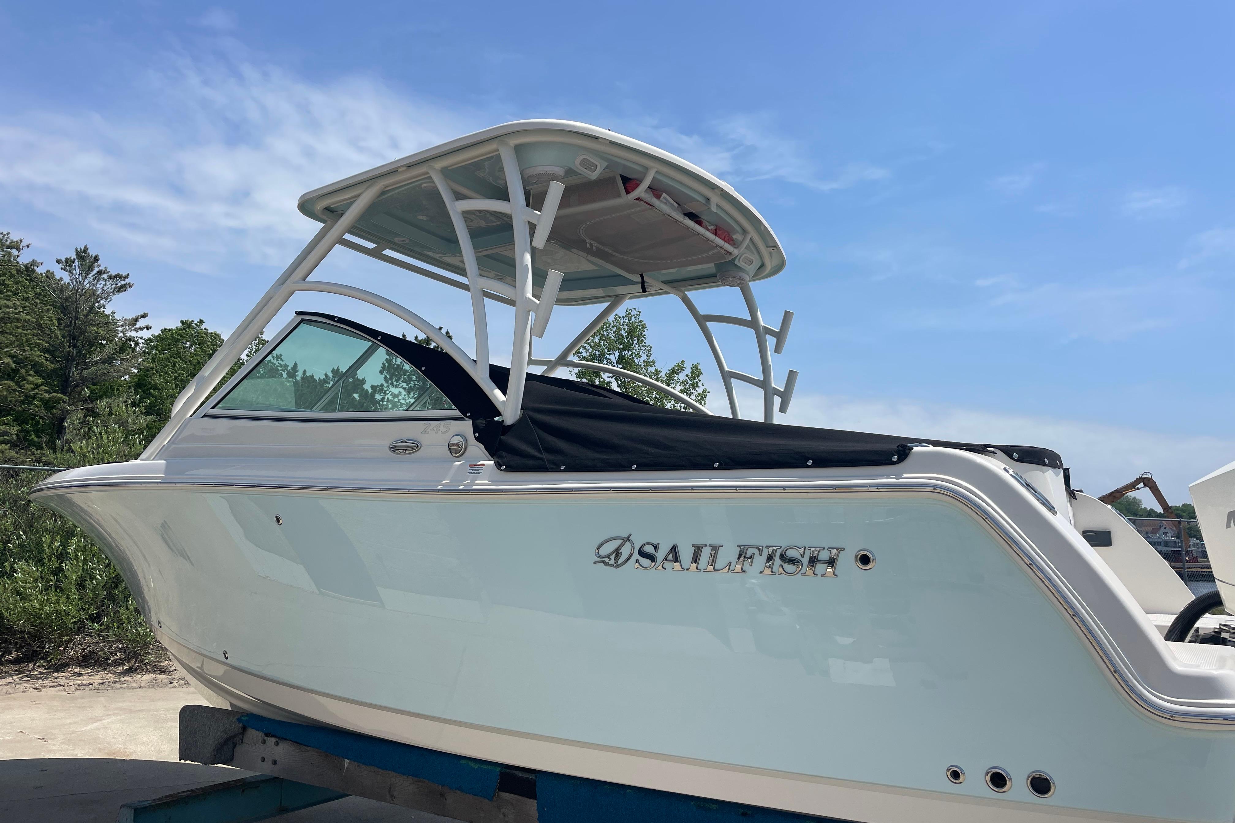 2022 Sailfish 245 DC boat with canopy, parked outdoors under a clear blue sky.