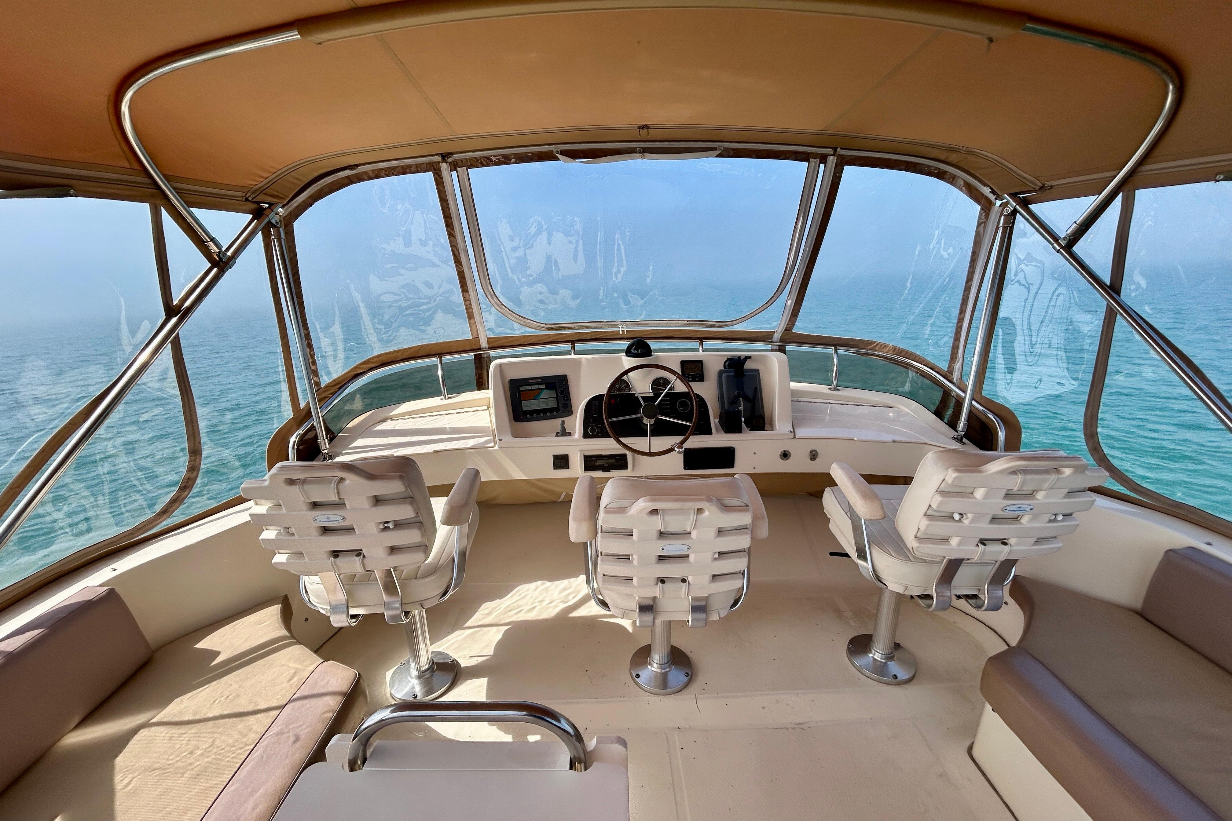 2006 Mainship 34 Trawler helm with ocean view, featuring three white captain chairs.
