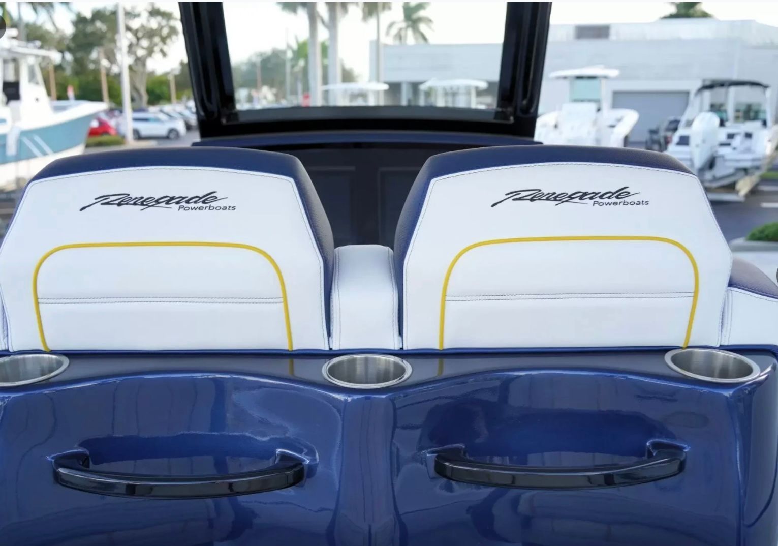 Rear view of two white boat seats with blue accents and cup holders.