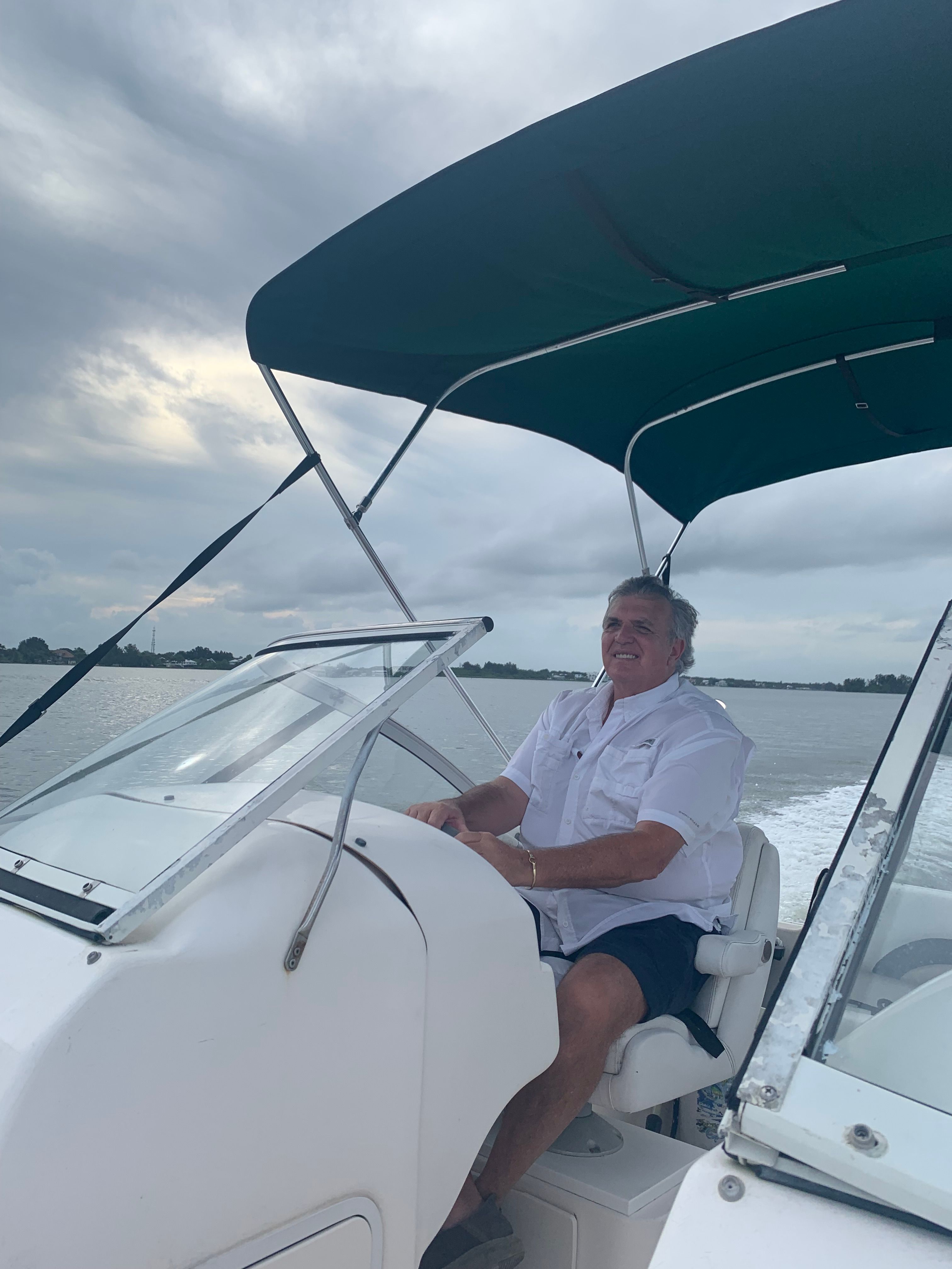 Man driving Hurricane SunDeck 217 OB boat on calm water.
