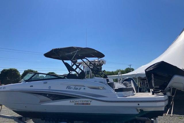 2024 Monterey M-65 boat with canopy, parked outdoors under clear blue sky.
