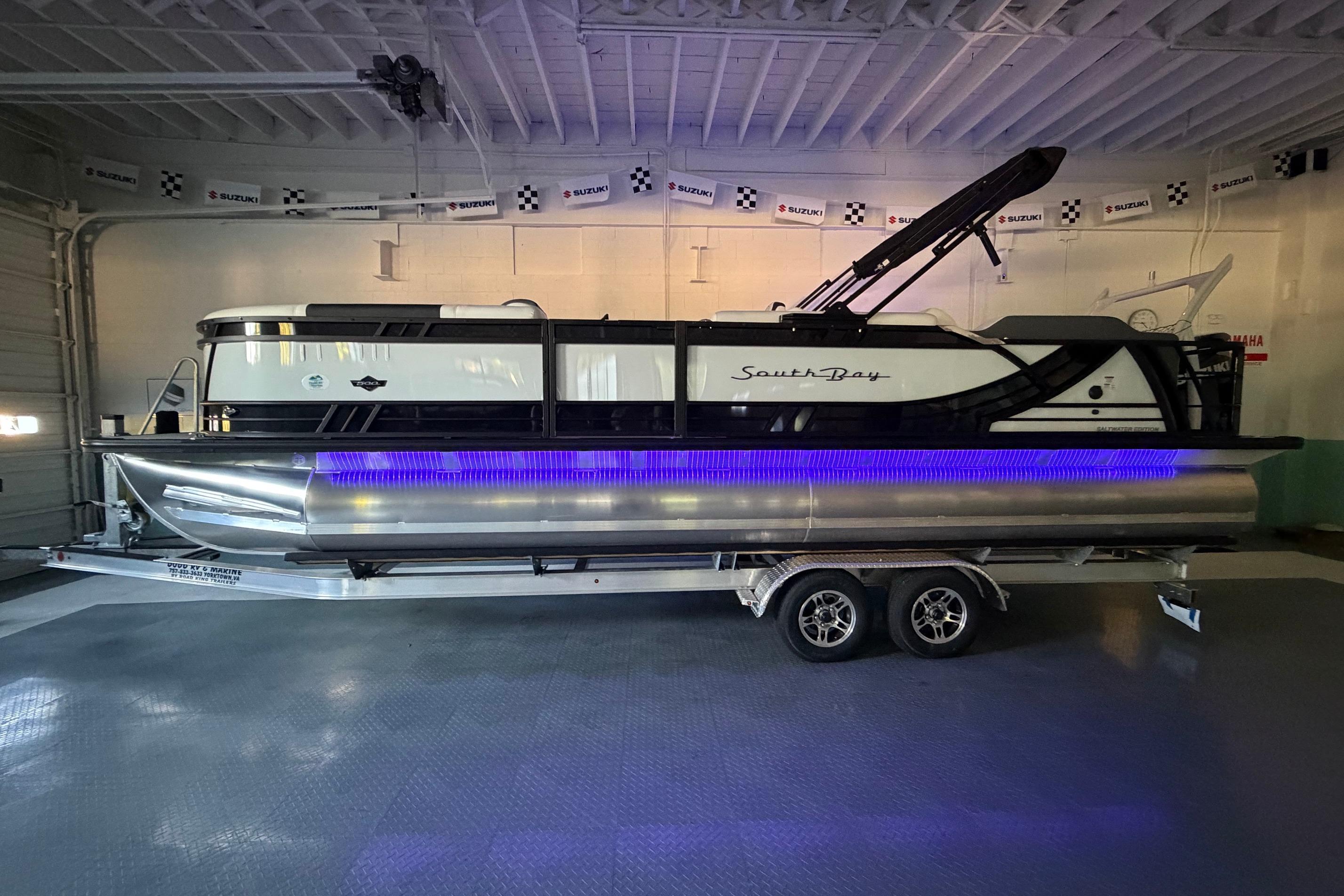 2026 South Bay 525SB2 pontoon boat with blue LED lights on a trailer in a garage.