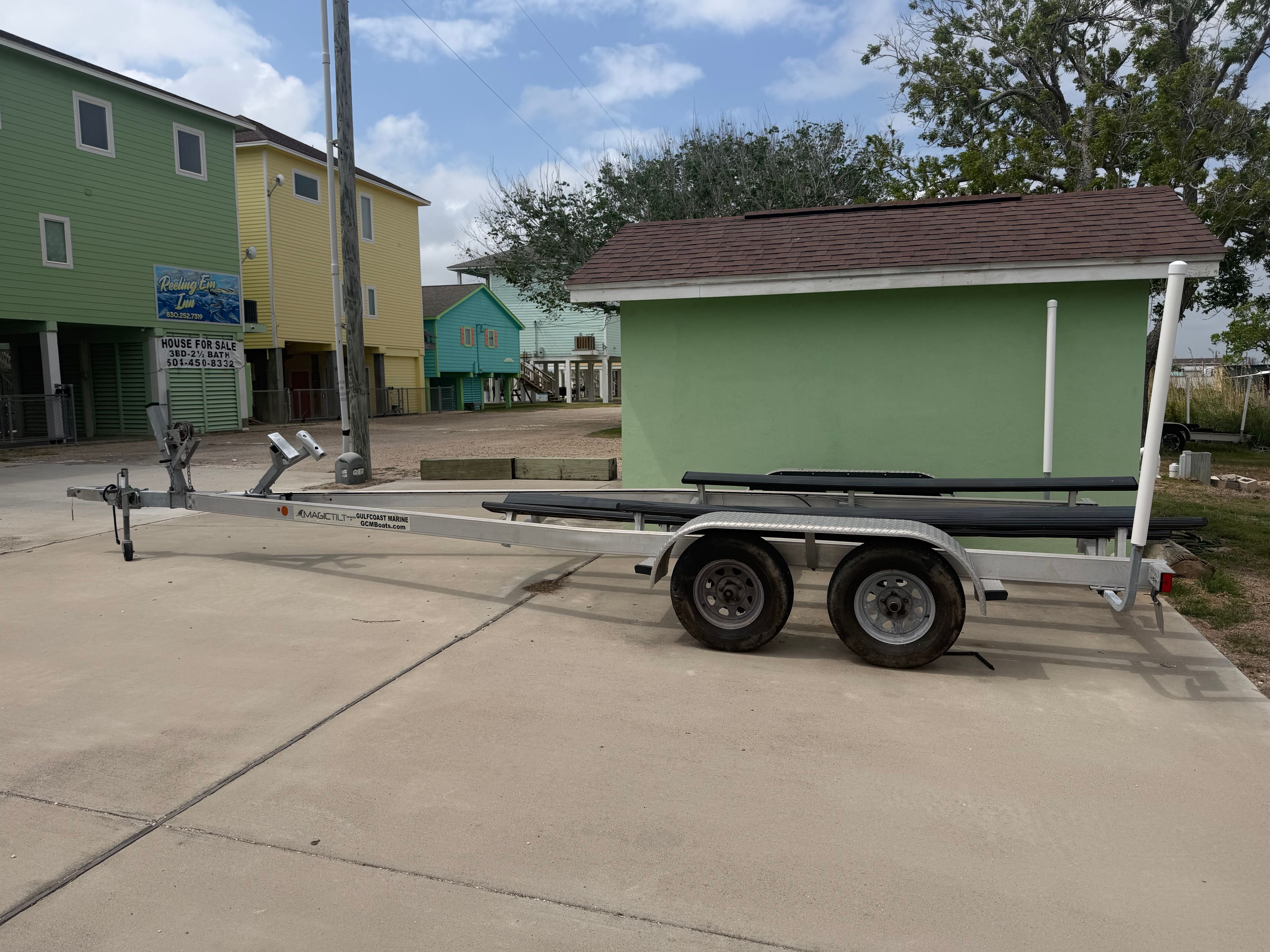 Boat trailer on concrete surface in front of colorful houses.