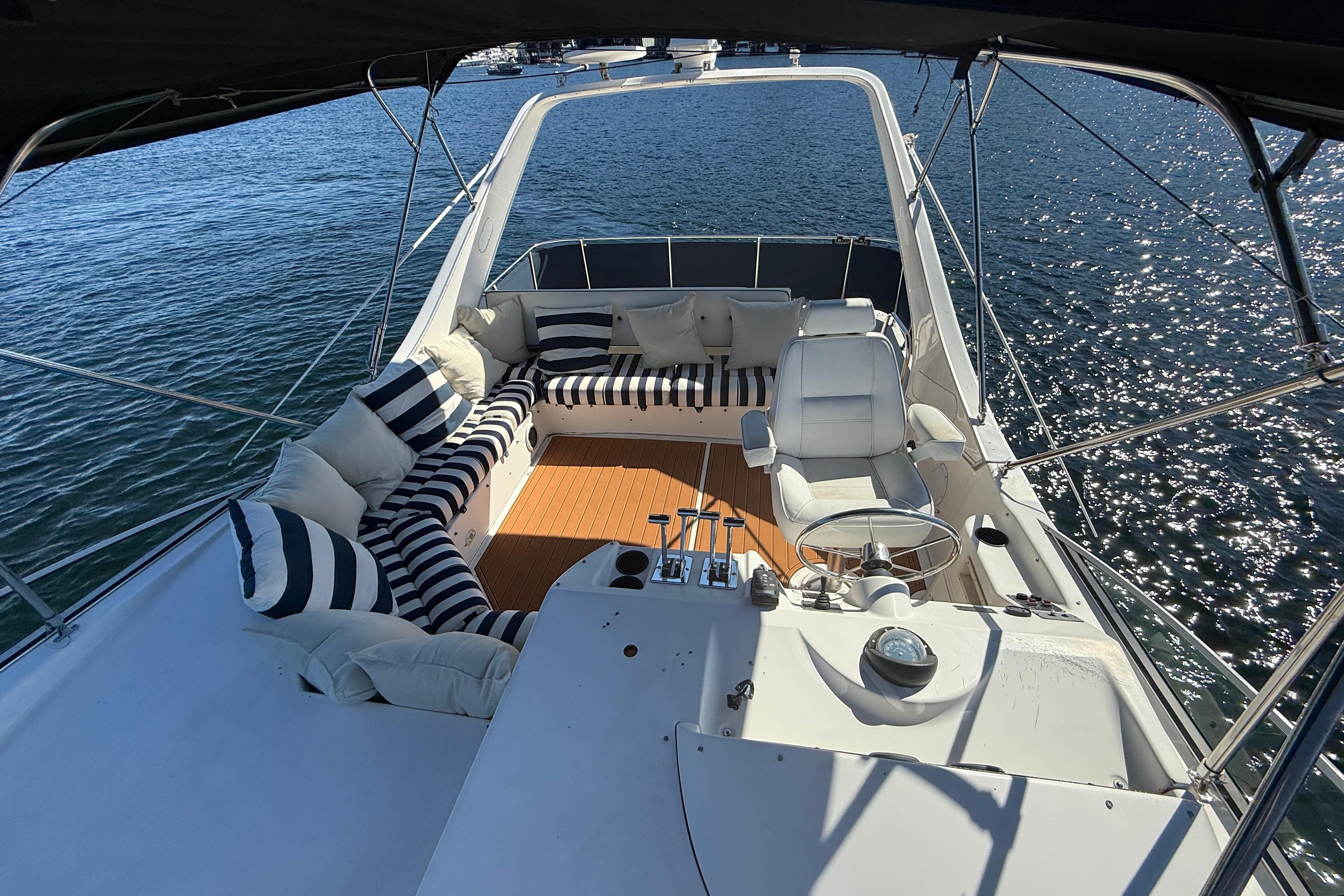 1997 Bayliner 3988 Command Bridge Motoryacht with striped seating, overlooking sparkling water.