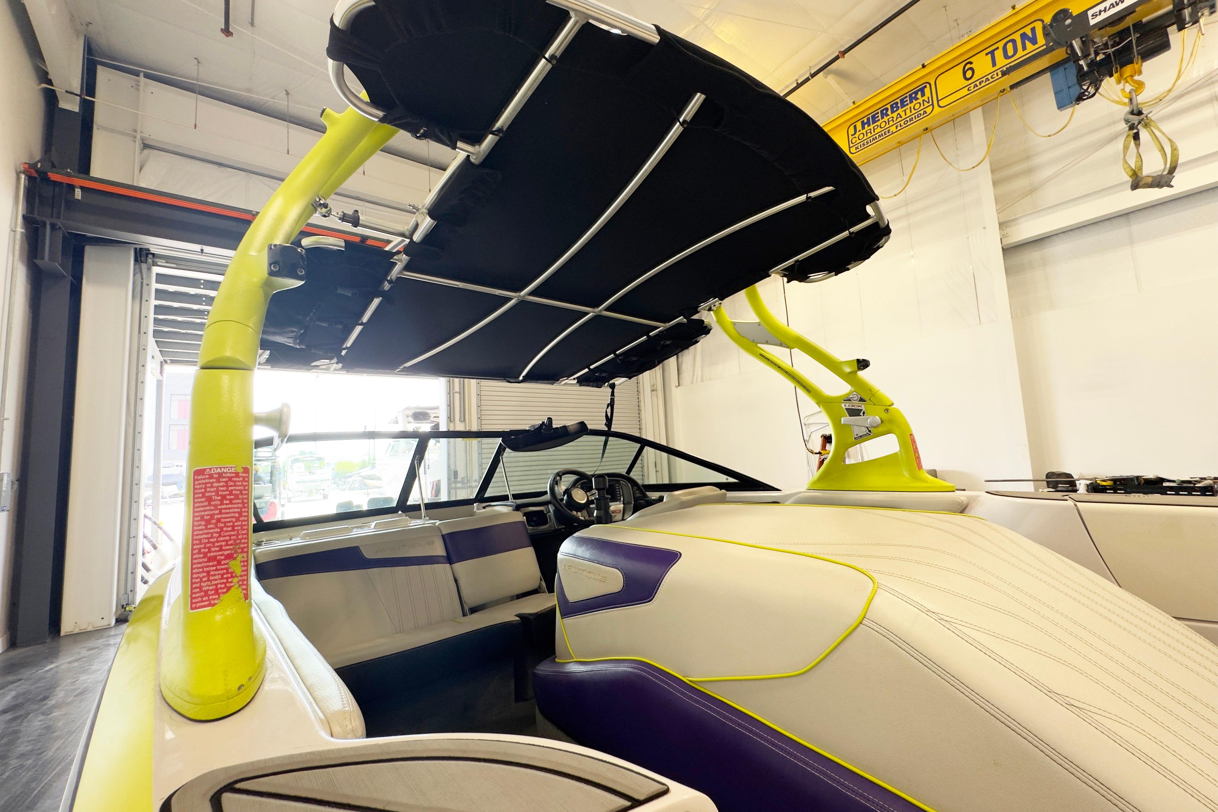 2014 Nautique Ski Nautique 200 Closed Bow boat with vibrant interior and canopy in a garage.