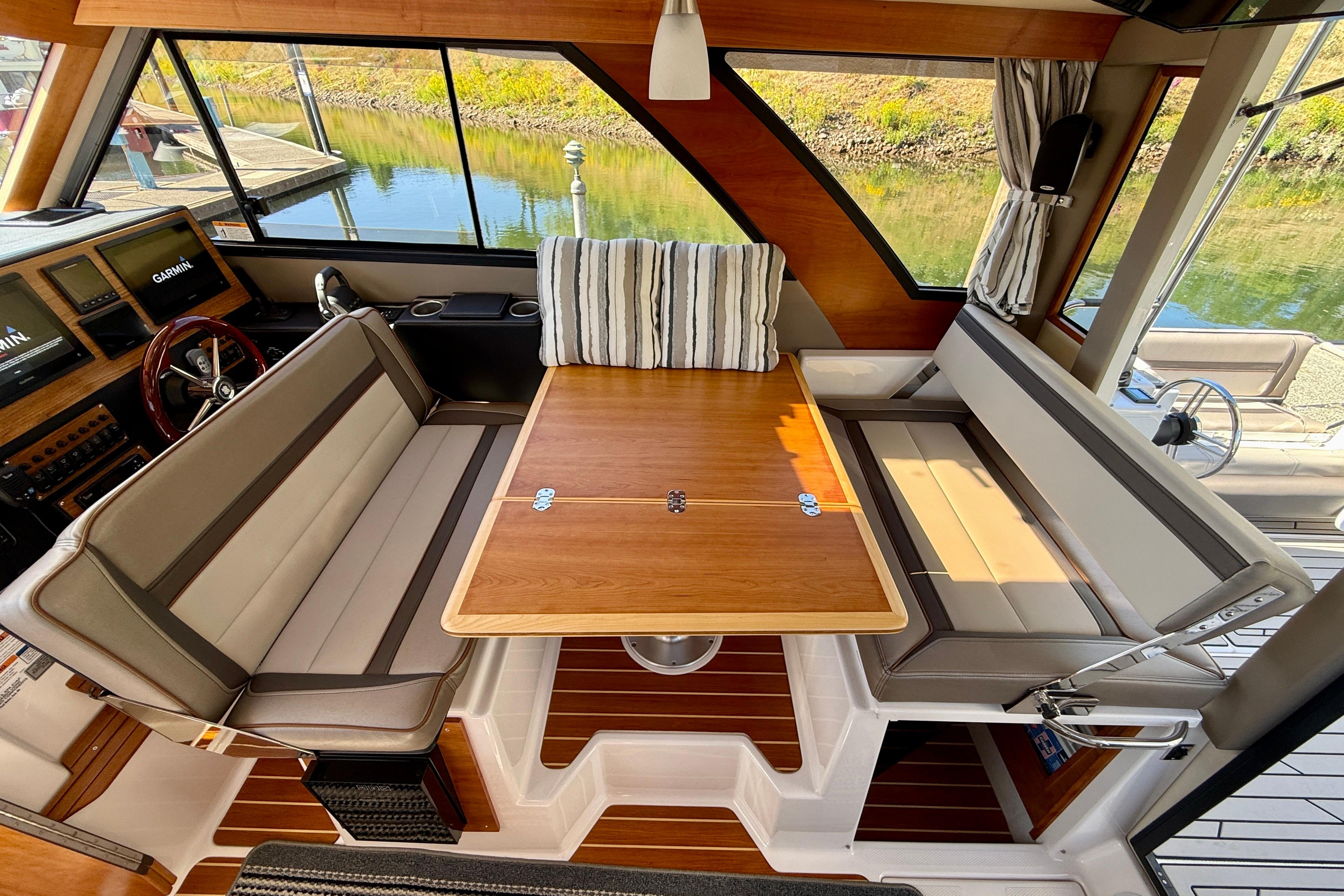 Interior of 2023 Cutwater C-30 Sedan with wood table and cushioned seating.