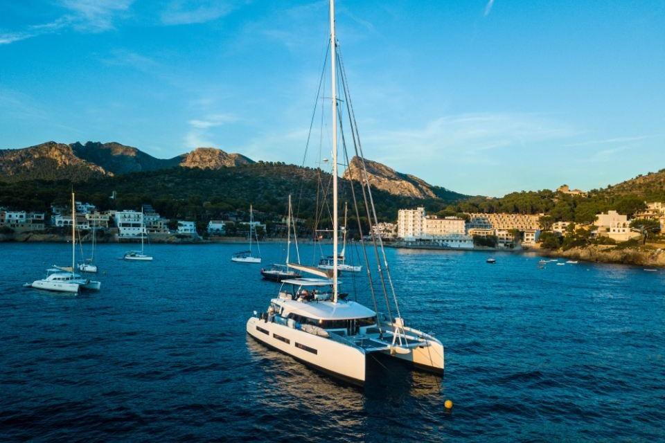 Luxurious 2018 Lagoon SEVENTY 7 catamaran anchored in scenic coastal bay.