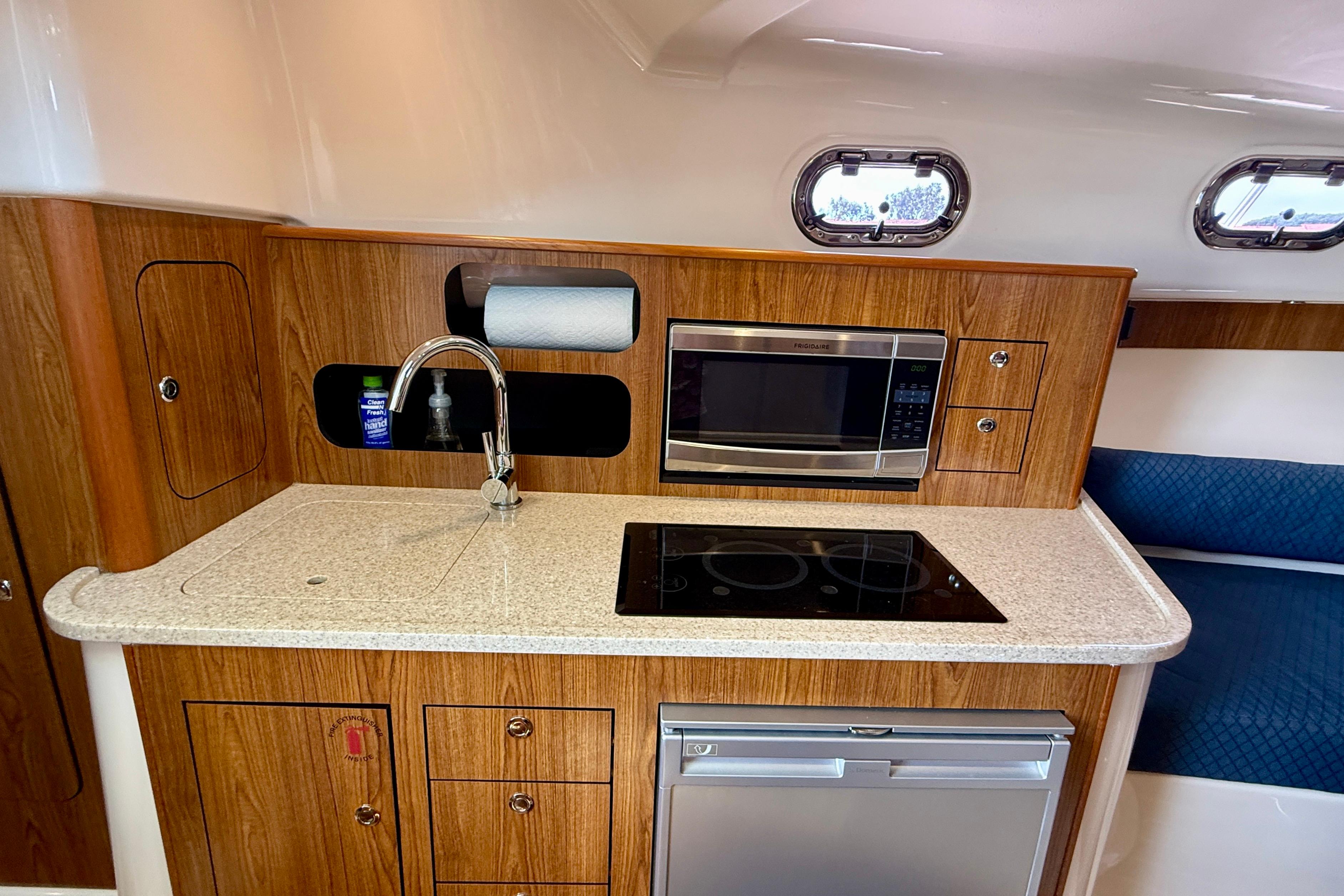 2012 Pursuit OS 345 Offshore boat kitchen with microwave, stove, and sink.