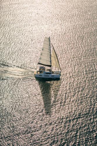 Aerial view of 2025 Lagoon 51 ICONIC sailing on shimmering water.