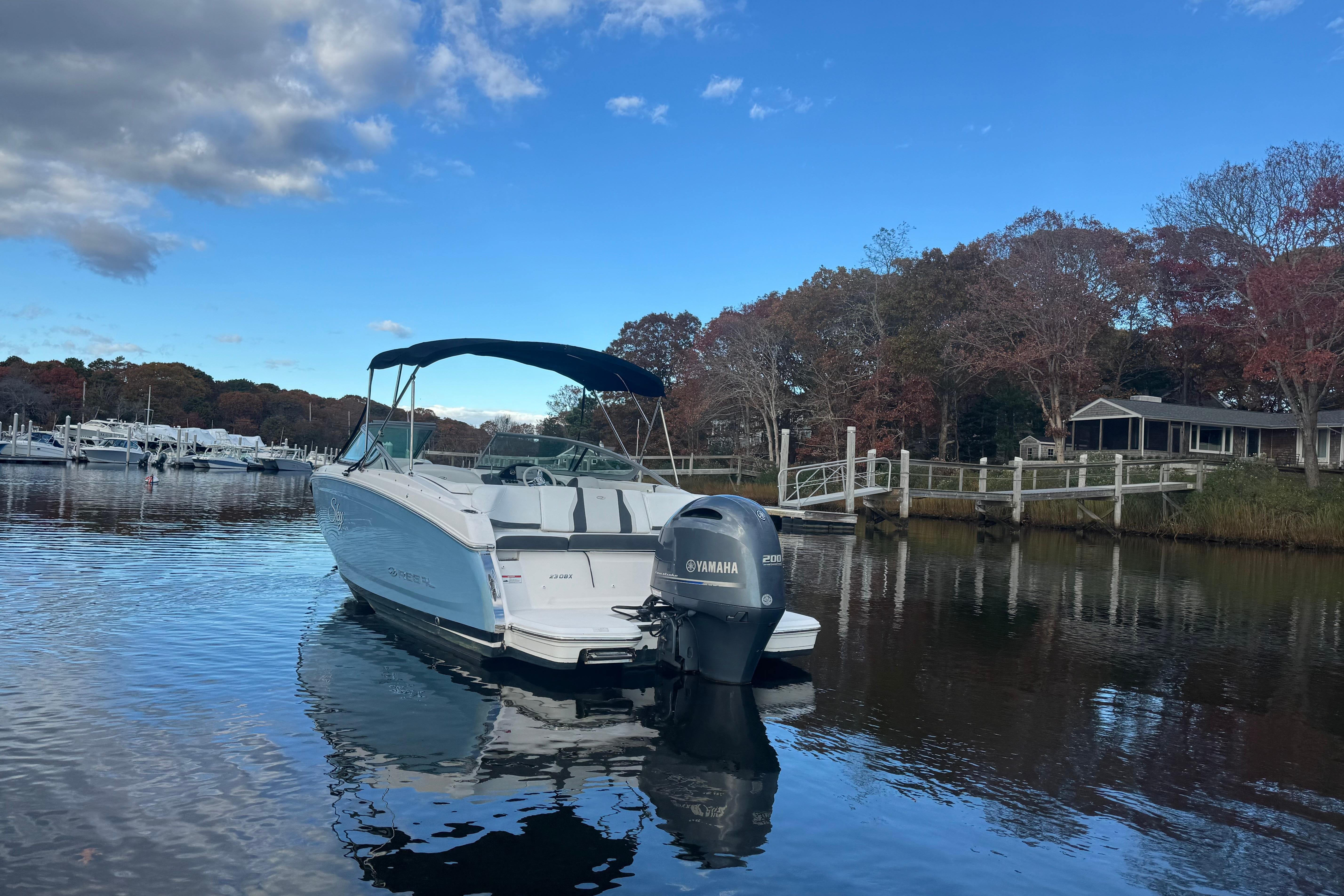 2017 Regal 23 OBX boat with Yamaha engine on calm water, surrounded by autumn trees.