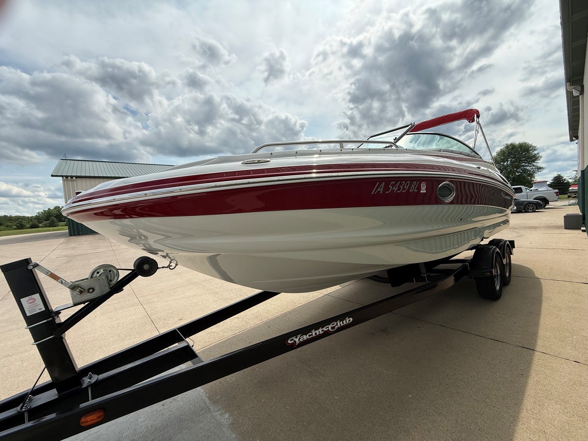 A 2012 Crownline 252 EX boat on a trailer, featuring red accents and a canopy.