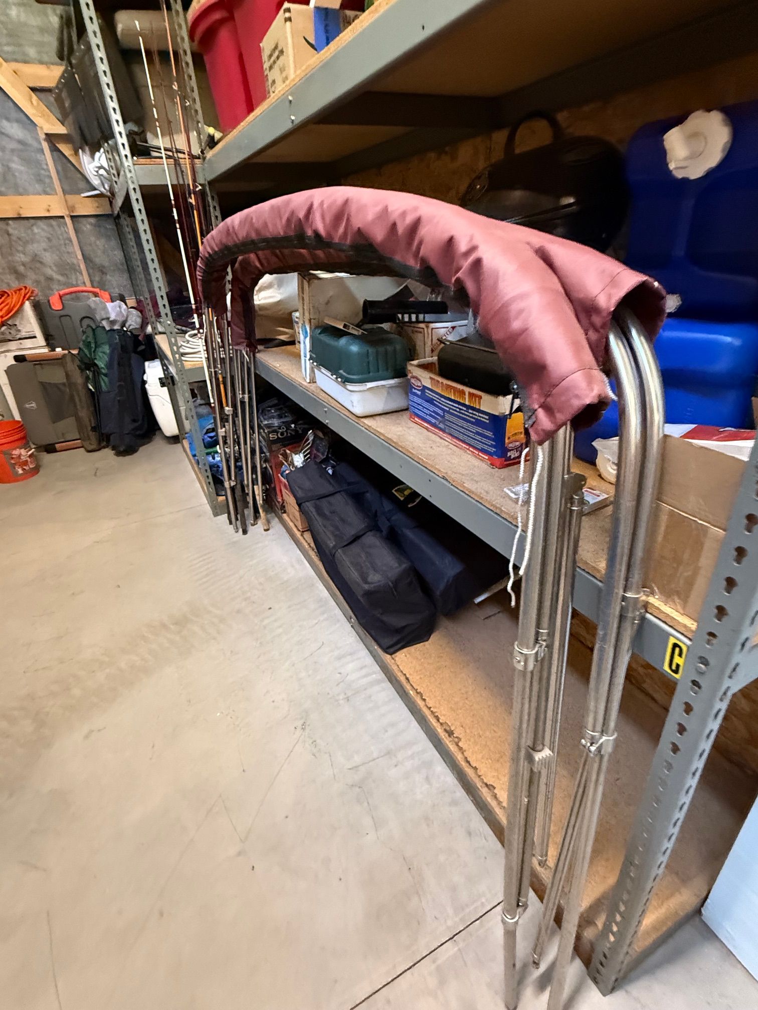 A folded Bimini top is stored on a shelf in a storage room.