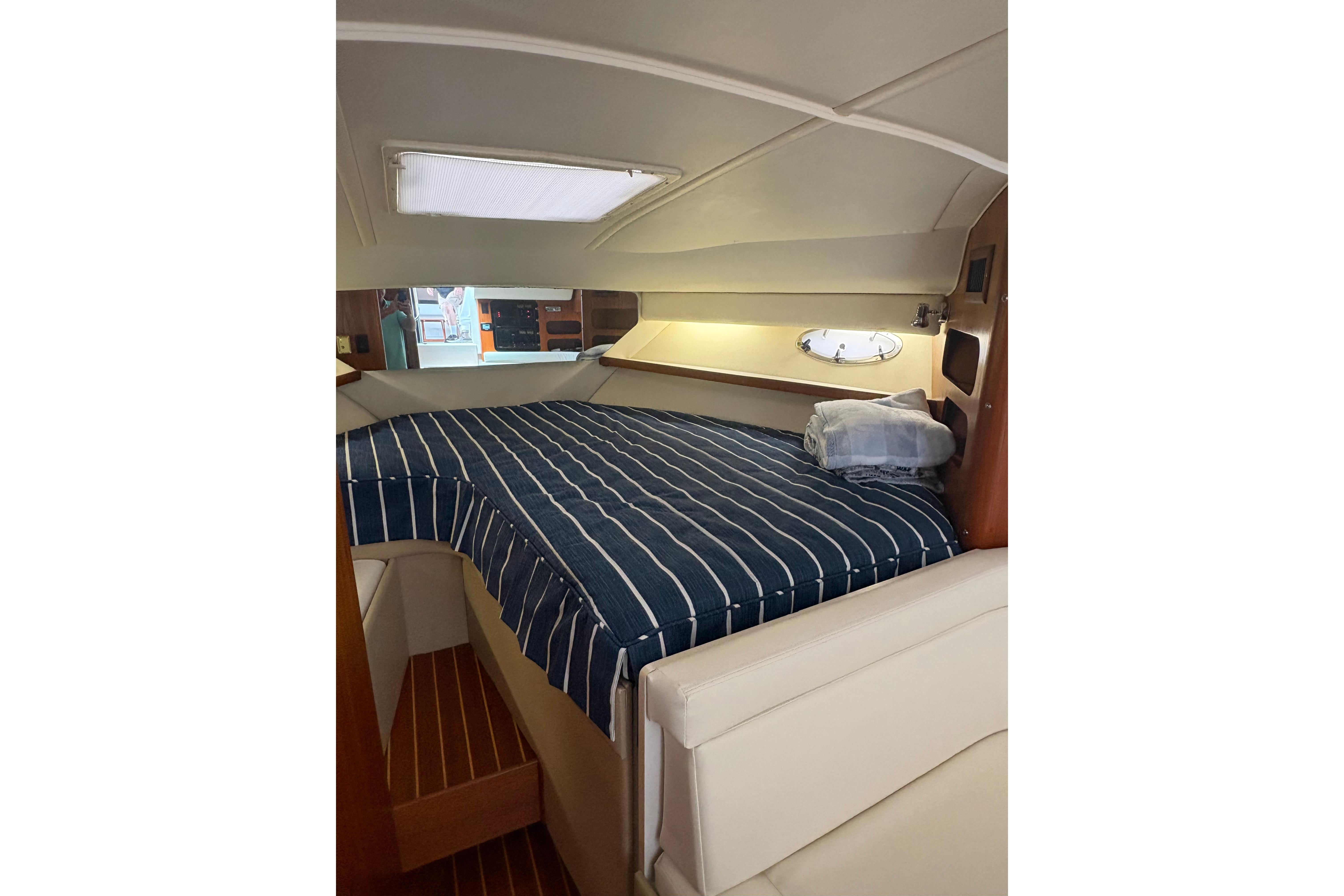 1999 Tiara Yachts 3100 Open cabin interior with striped bedding and wooden accents.