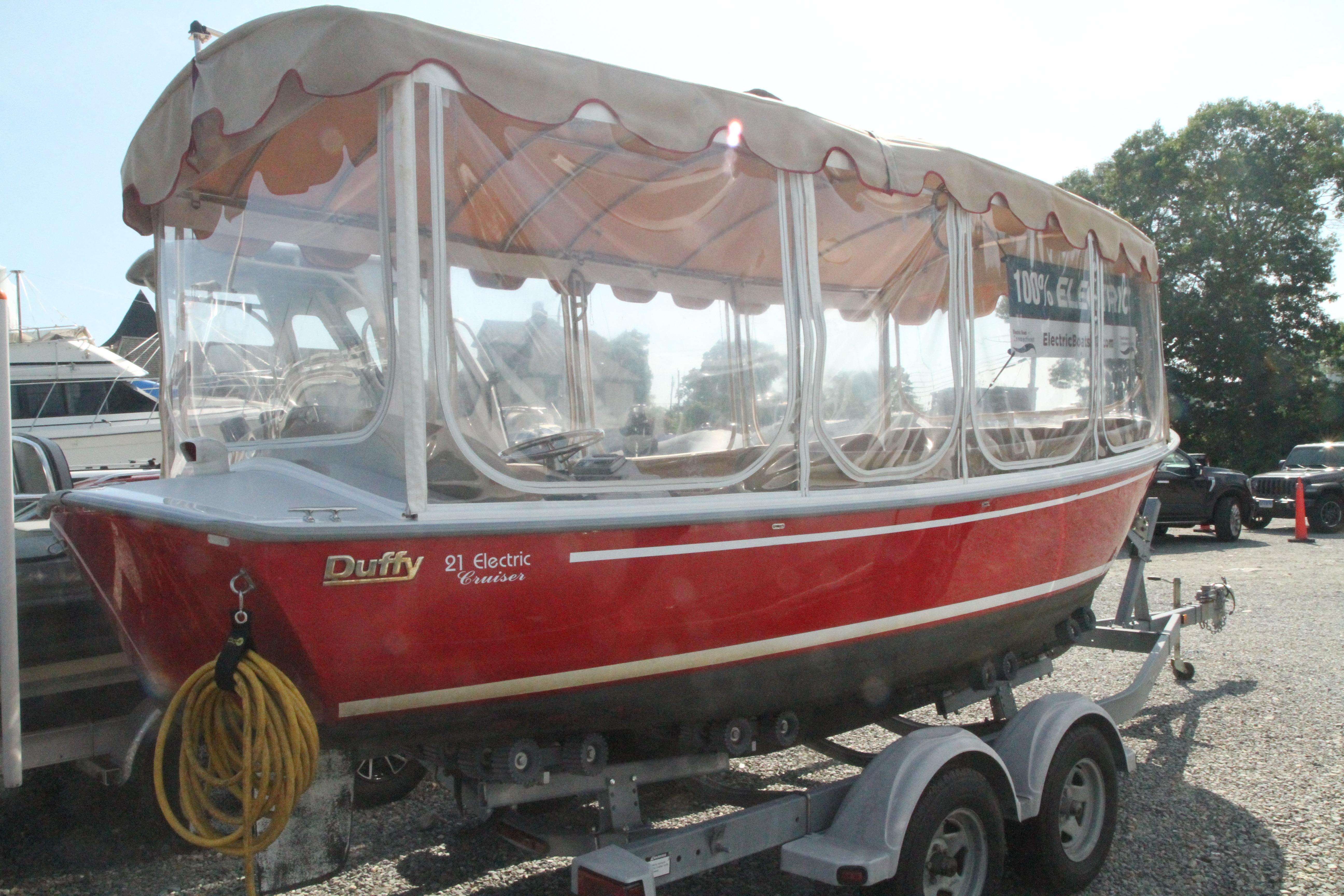 Red 2004 Duffy 21 Classic electric boat on trailer, parked outdoors.