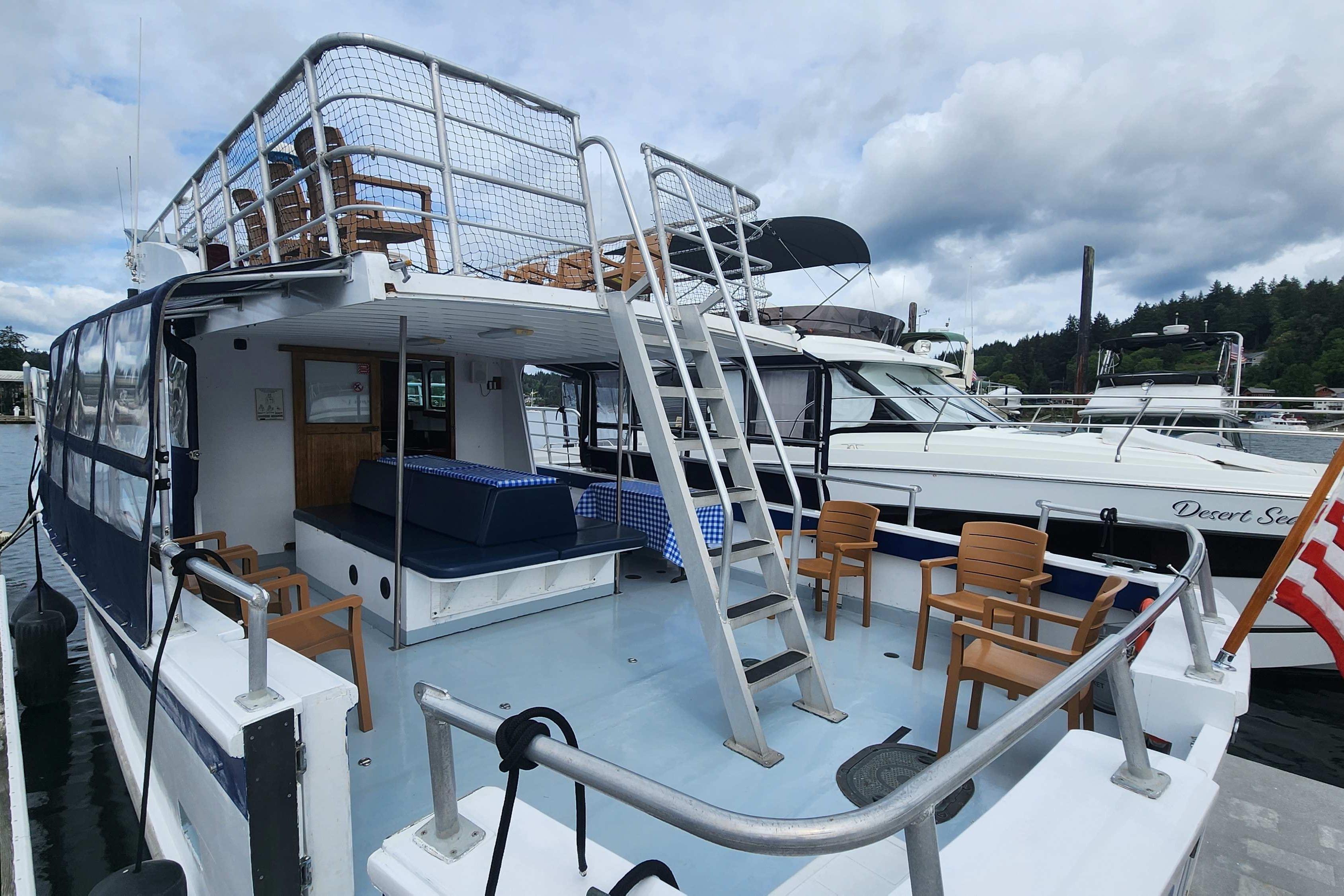 1964 Grandy Tour Boat with seating and upper deck, docked at a marina under cloudy skies.