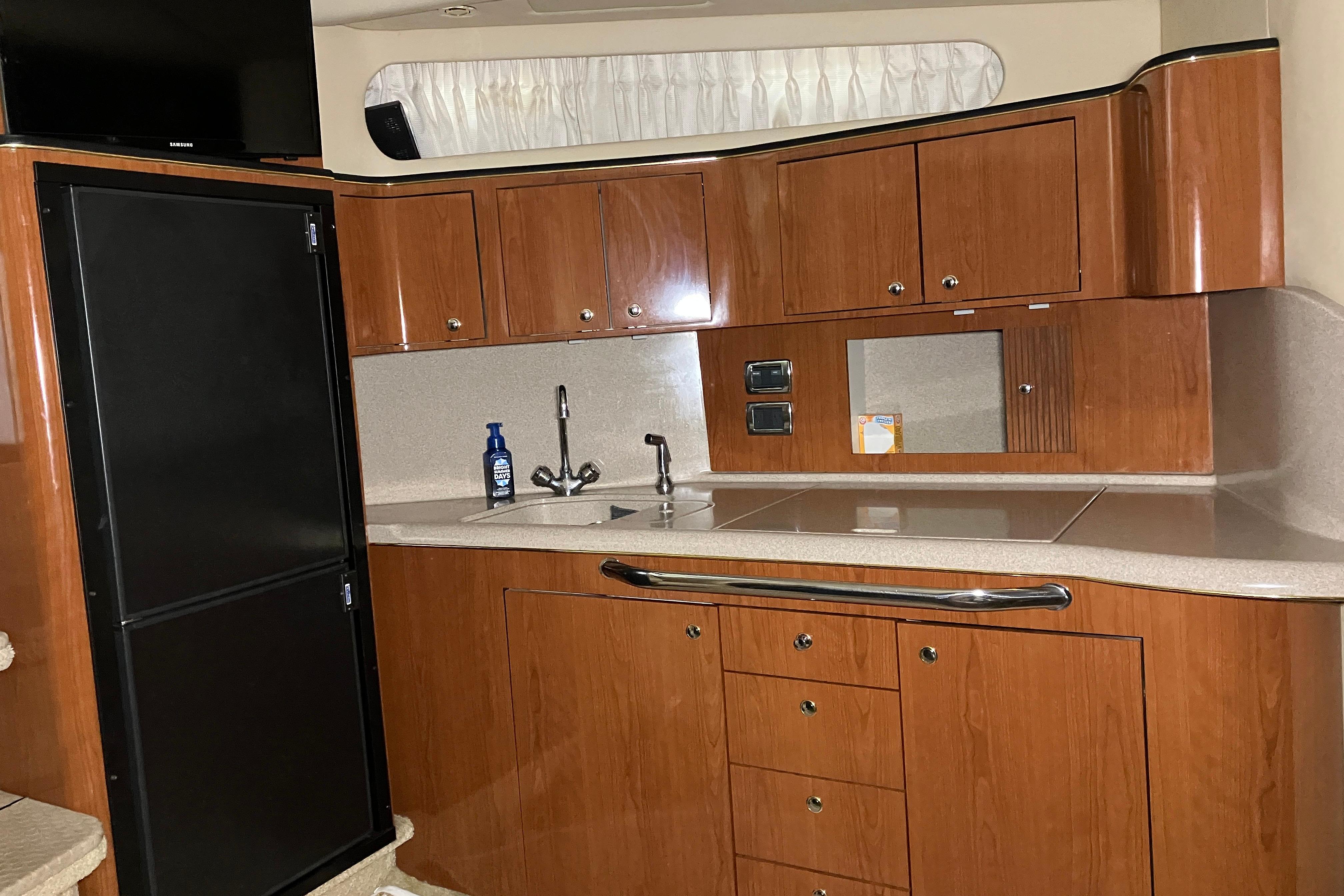 Interior of 2002 Sea Ray 410 Sundancer yacht kitchen with wood cabinets and modern appliances.