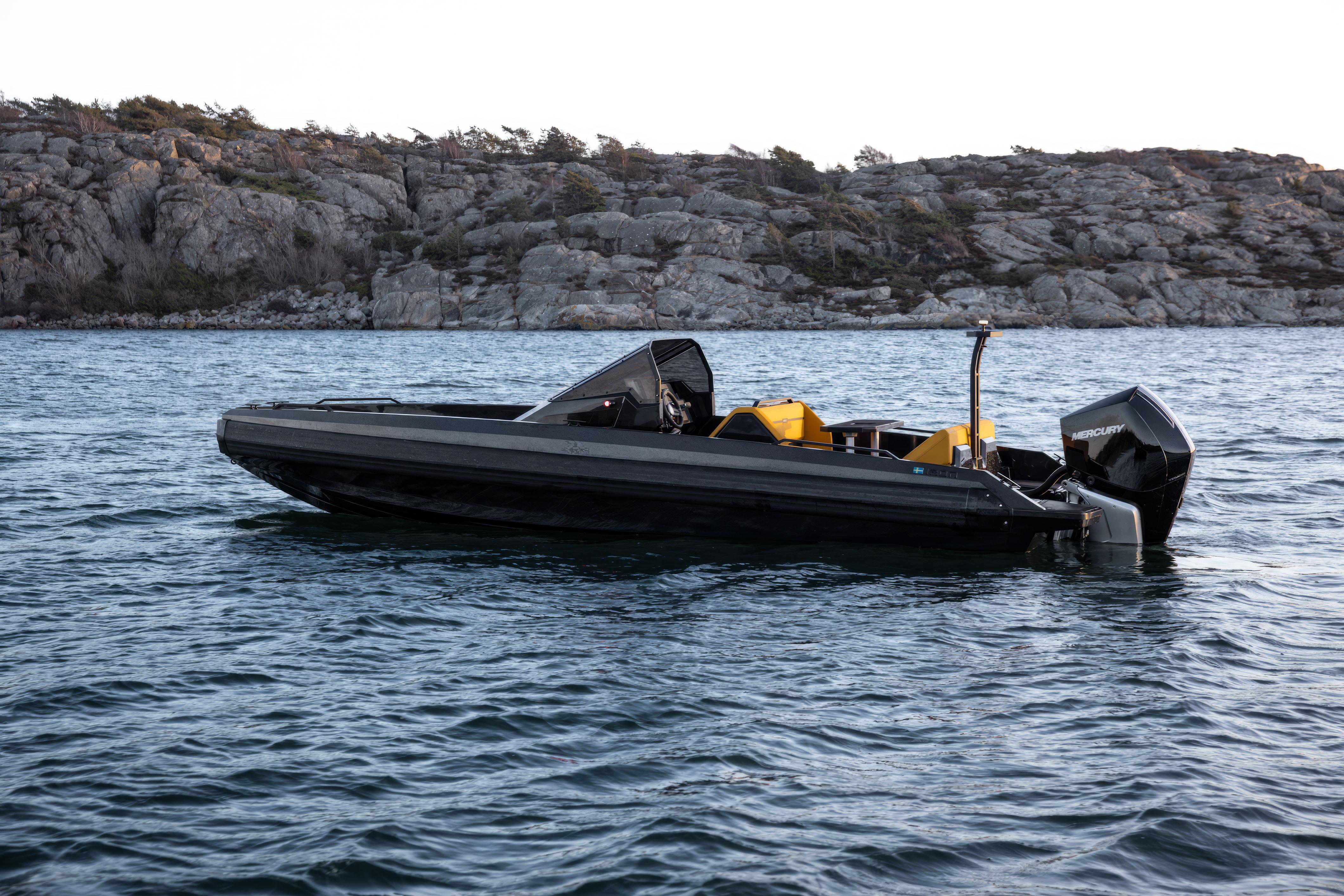 2026 Iron 767 T-top boat on water near rocky shoreline.