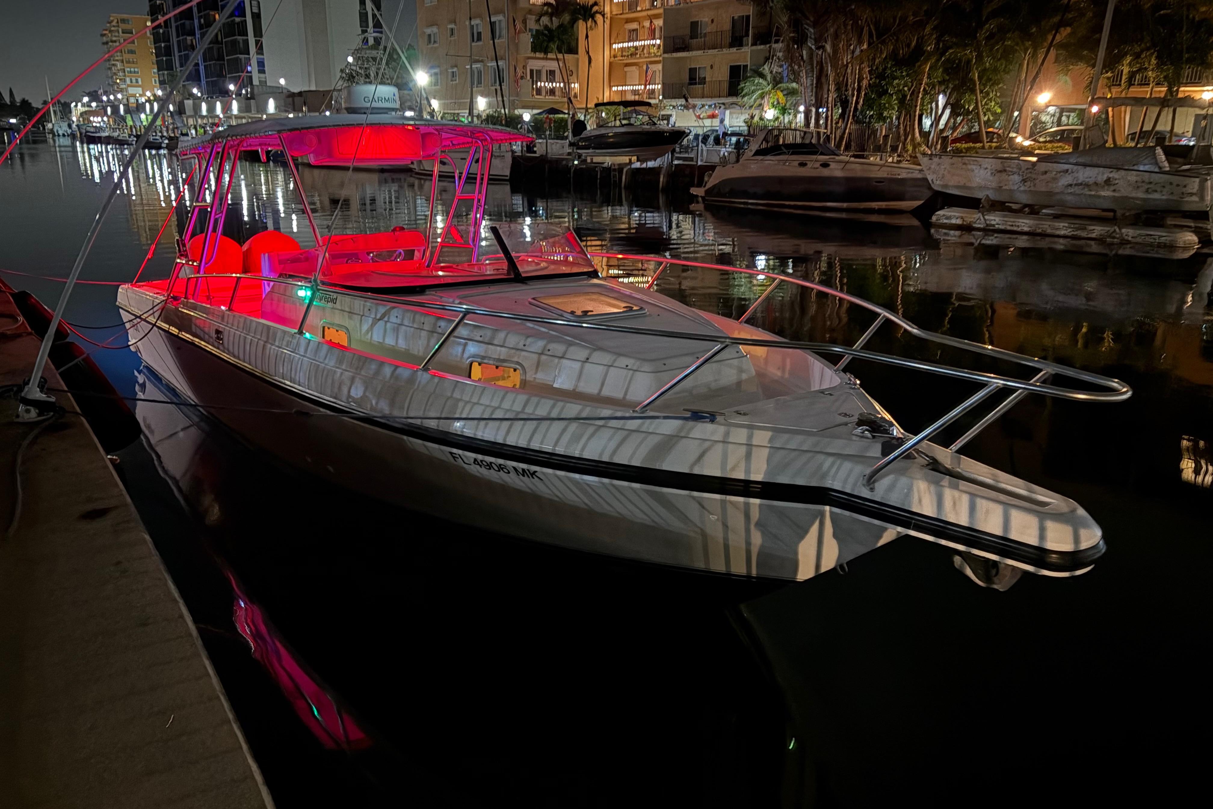 1998 Intrepid 339 Walkaround boat docked at night with vibrant red lighting.