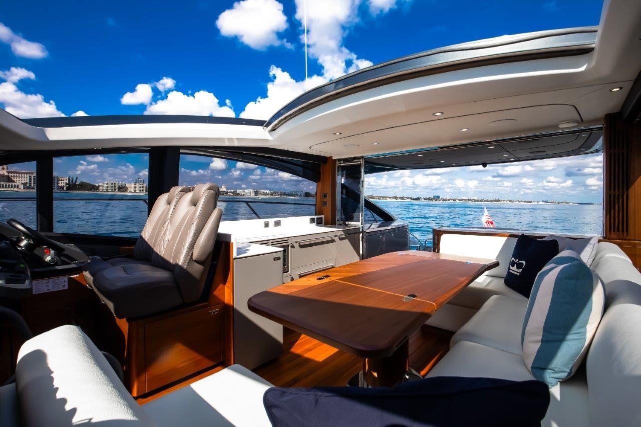Luxurious interior of a Princess V55 yacht with elegant seating and a wooden table under blue skies.