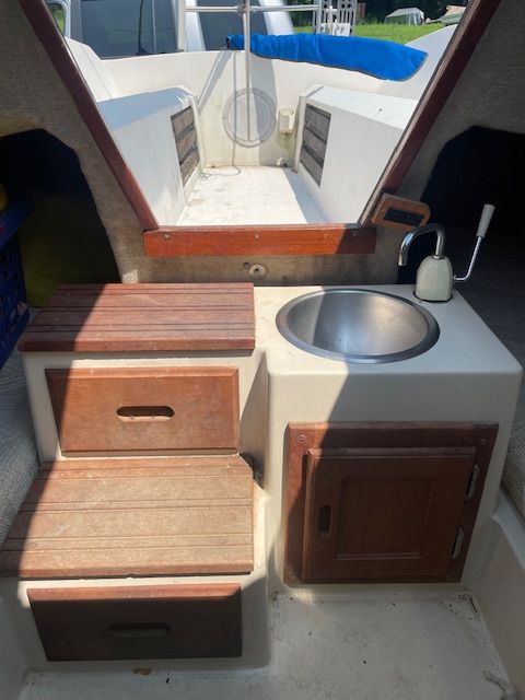 Interior of a 1986 Wellcraft Starwind 19 with a sink and wooden cabinets.