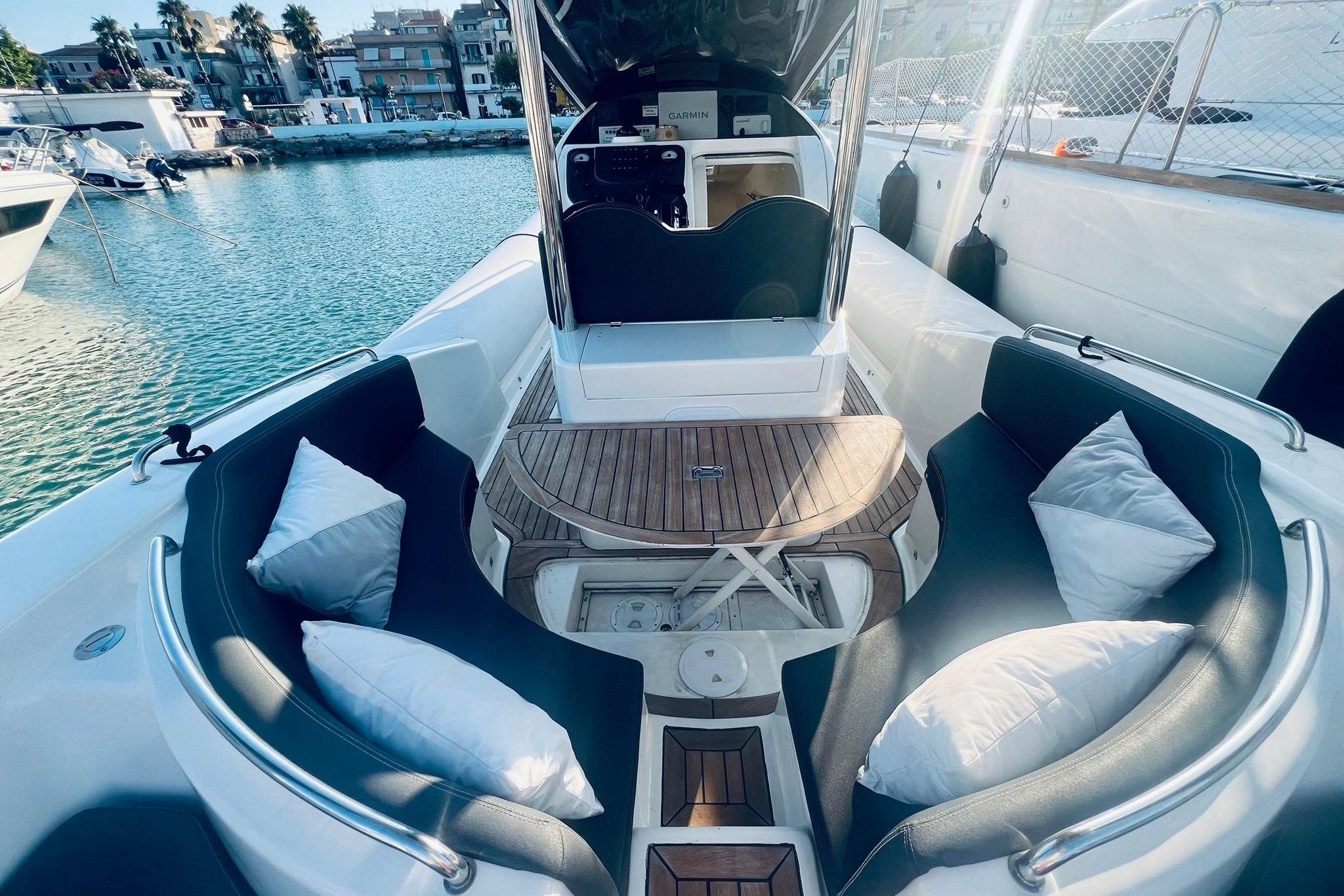 2023 Domar D-10 boat interior with cushioned seating and wooden table in a marina setting.