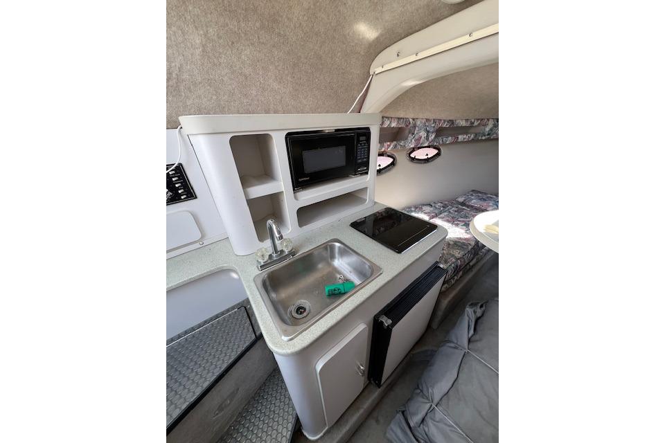 1997 Crownline 250 CR boat interior with kitchenette, sink, microwave, and cozy seating area.