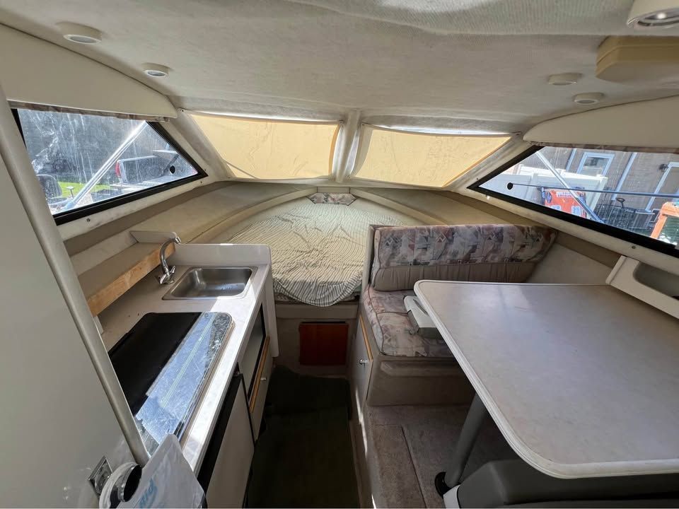 Interior of a 1999 Bayliner 2452 with kitchenette and seating area.