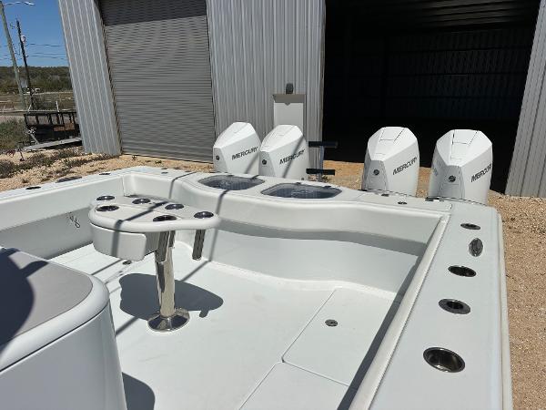2022 Freeman 42LR boat with four Mercury outboard engines, docked near a metal building.