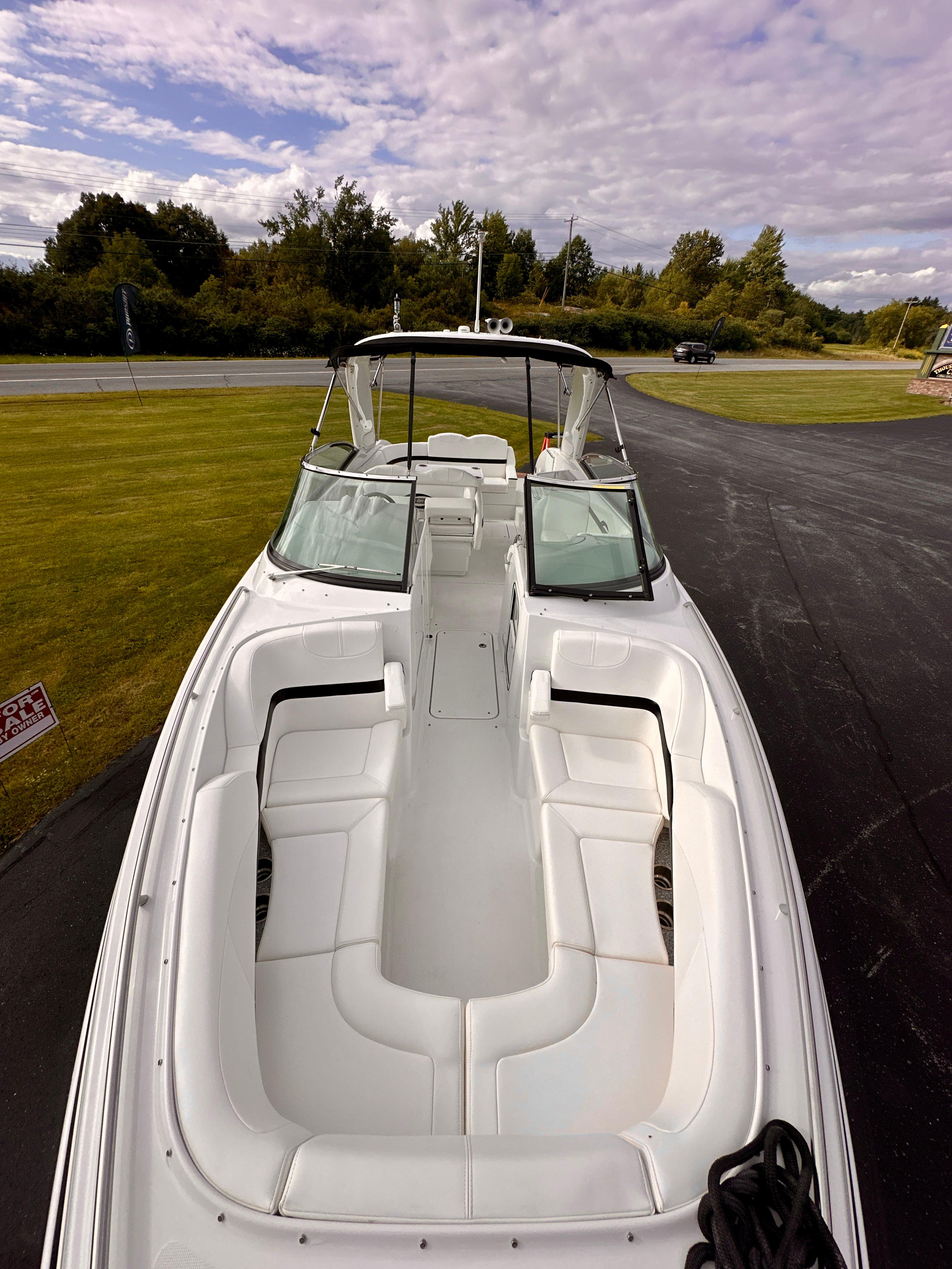 2008 Formula 310 Bowrider boat with spacious seating, parked on a driveway under a cloudy sky.