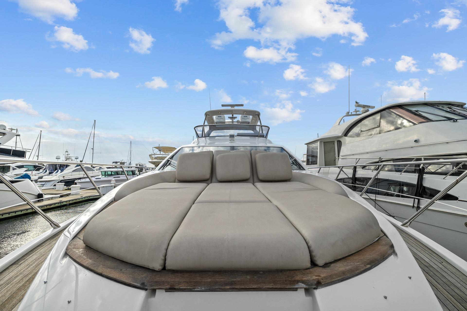 Luxurious 2019 Azimut 55 yacht with spacious sunbed, docked at marina under blue sky.