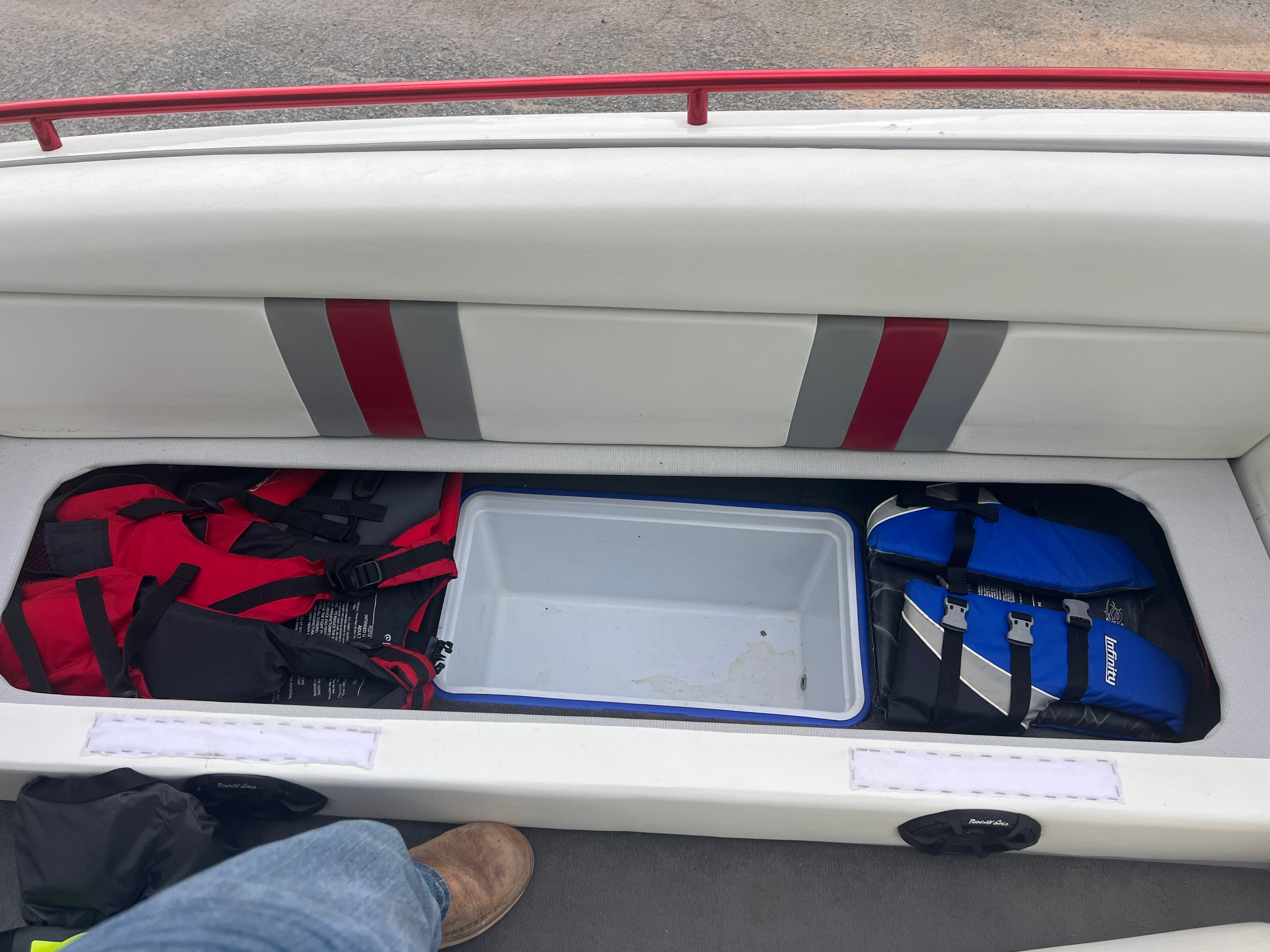 An open storage compartment with life jackets and a cooler.