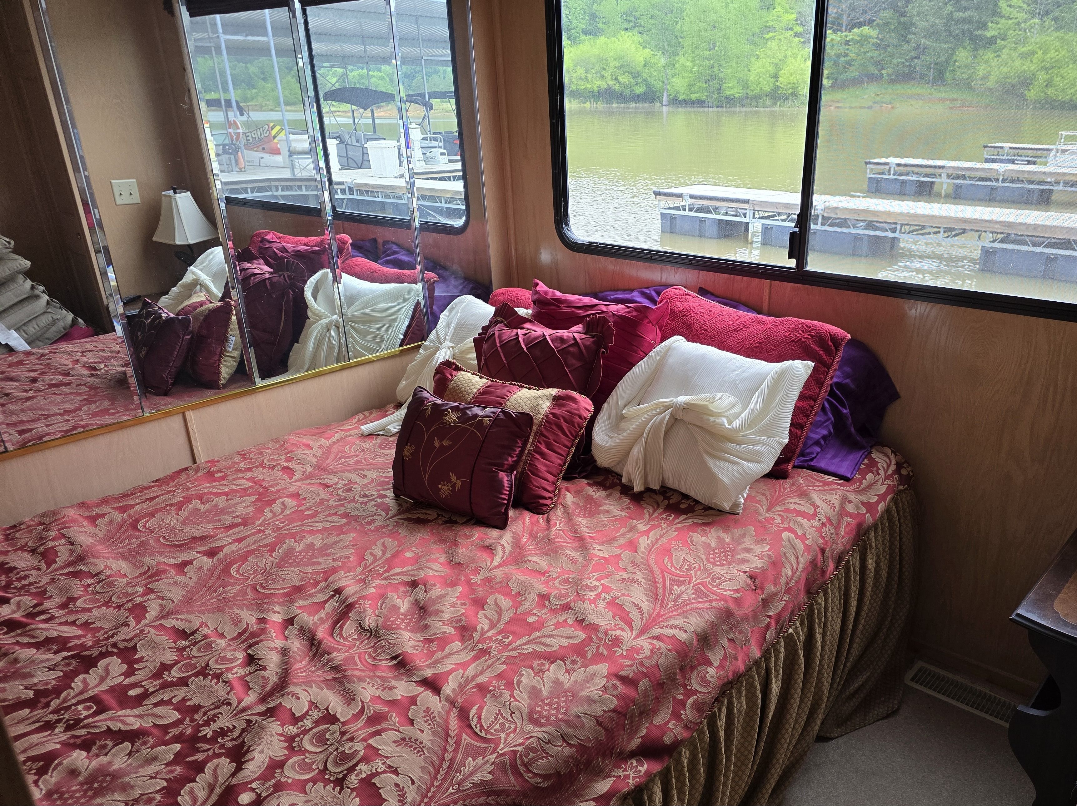 Bedroom interior of a 1998 Sumerset houseboat with elegant bedding and large window view.