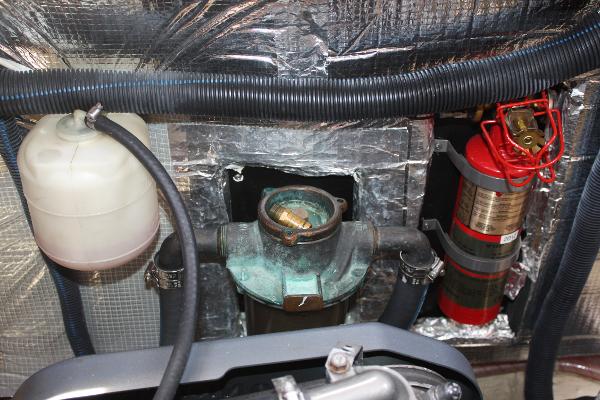 An engine compartment with hoses, a fire extinguisher, and a coolant reservoir.