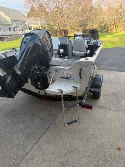 A Crestliner boat on a trailer with an outboard motor and ladder.