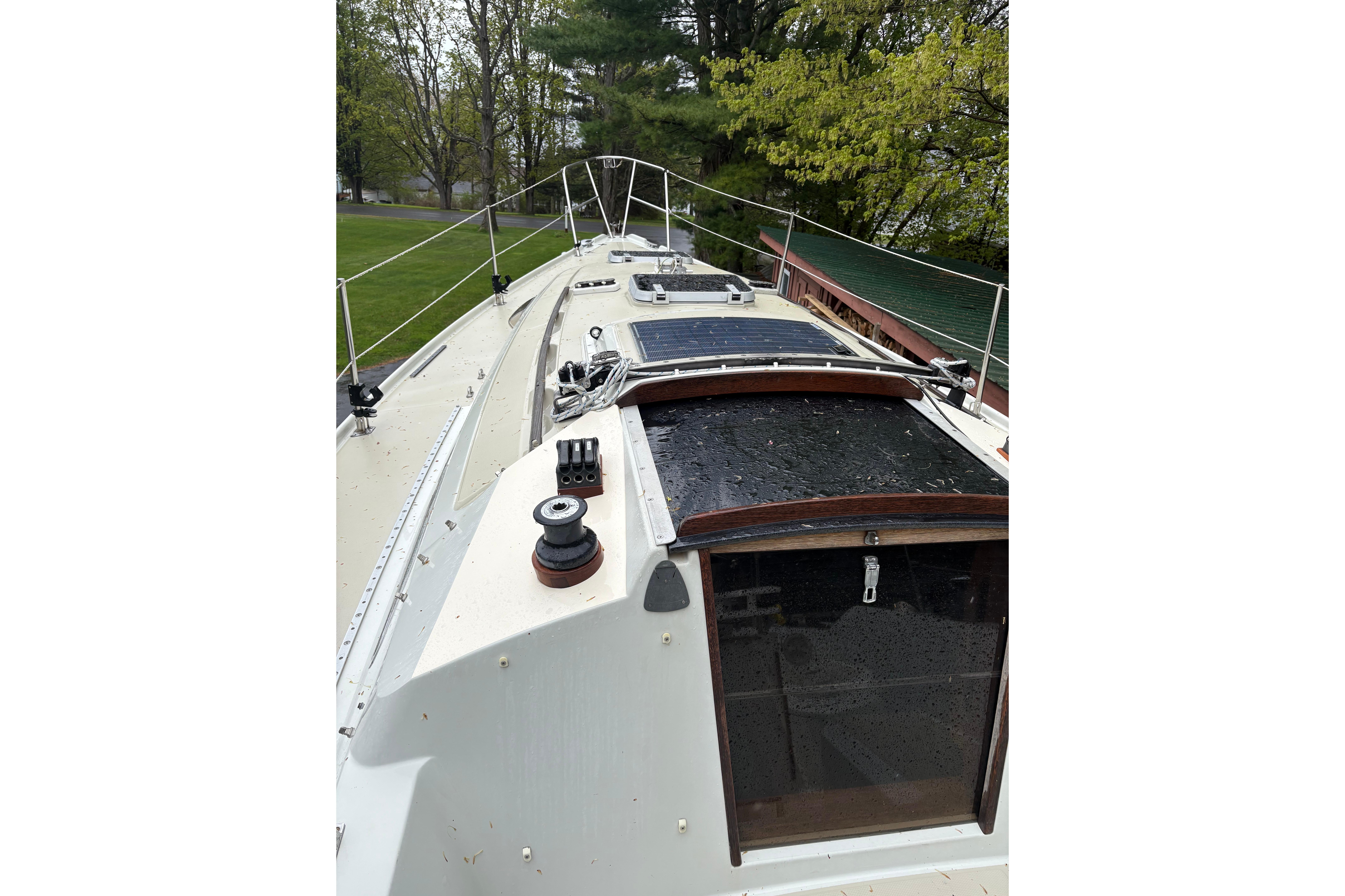 1987 Ericson 28/2 sailboat deck with winches and hatch, surrounded by greenery.