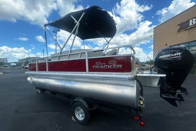 2026 Sun Tracker Bass Buggy 18 DLX pontoon boat with Mercury outboard motor, parked outdoors.