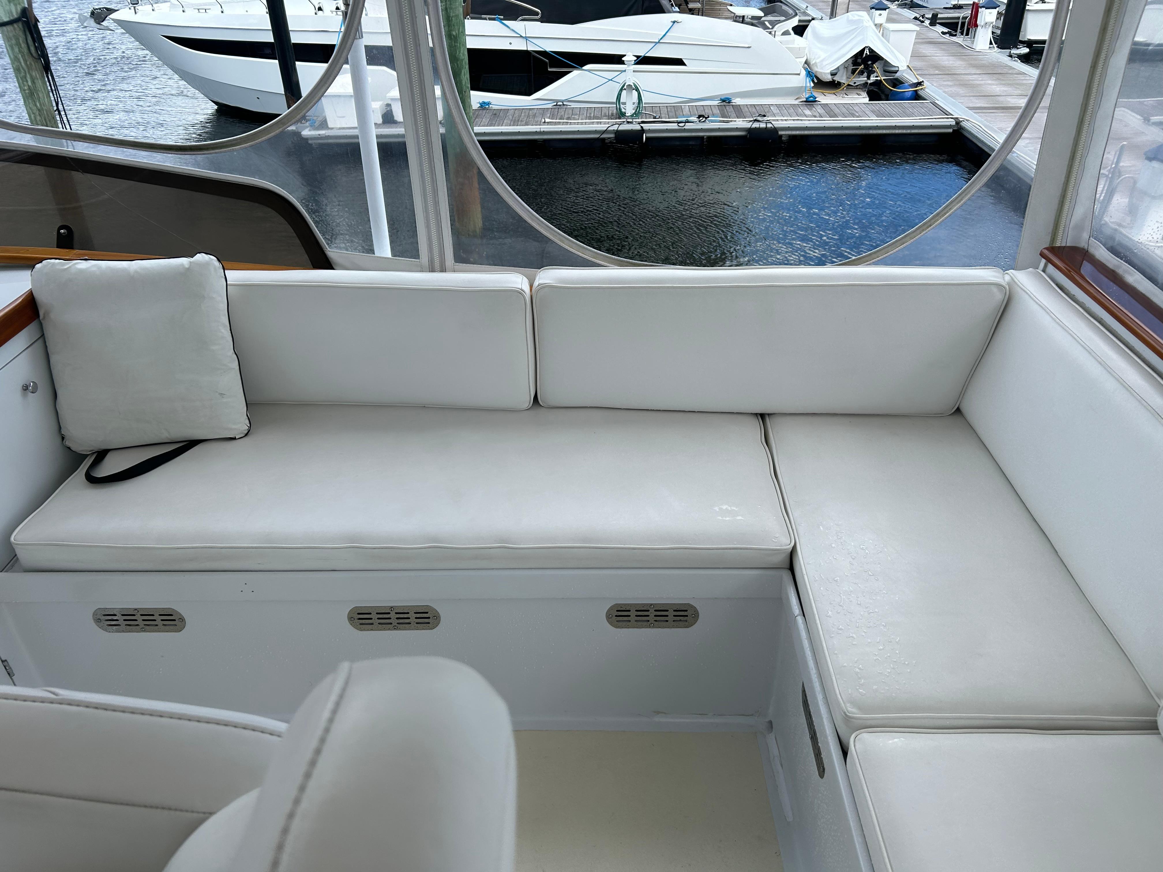 1987 Lyman-Morse Downeast Flybridge interior with white seating, docked boats visible outside.