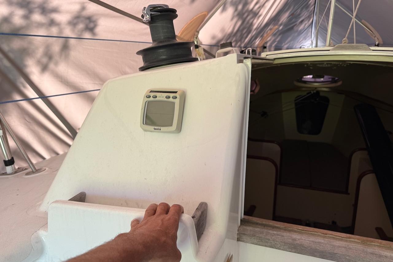2007 Hallett 33 sailboat cockpit with navigation equipment and hand on the hatch.
