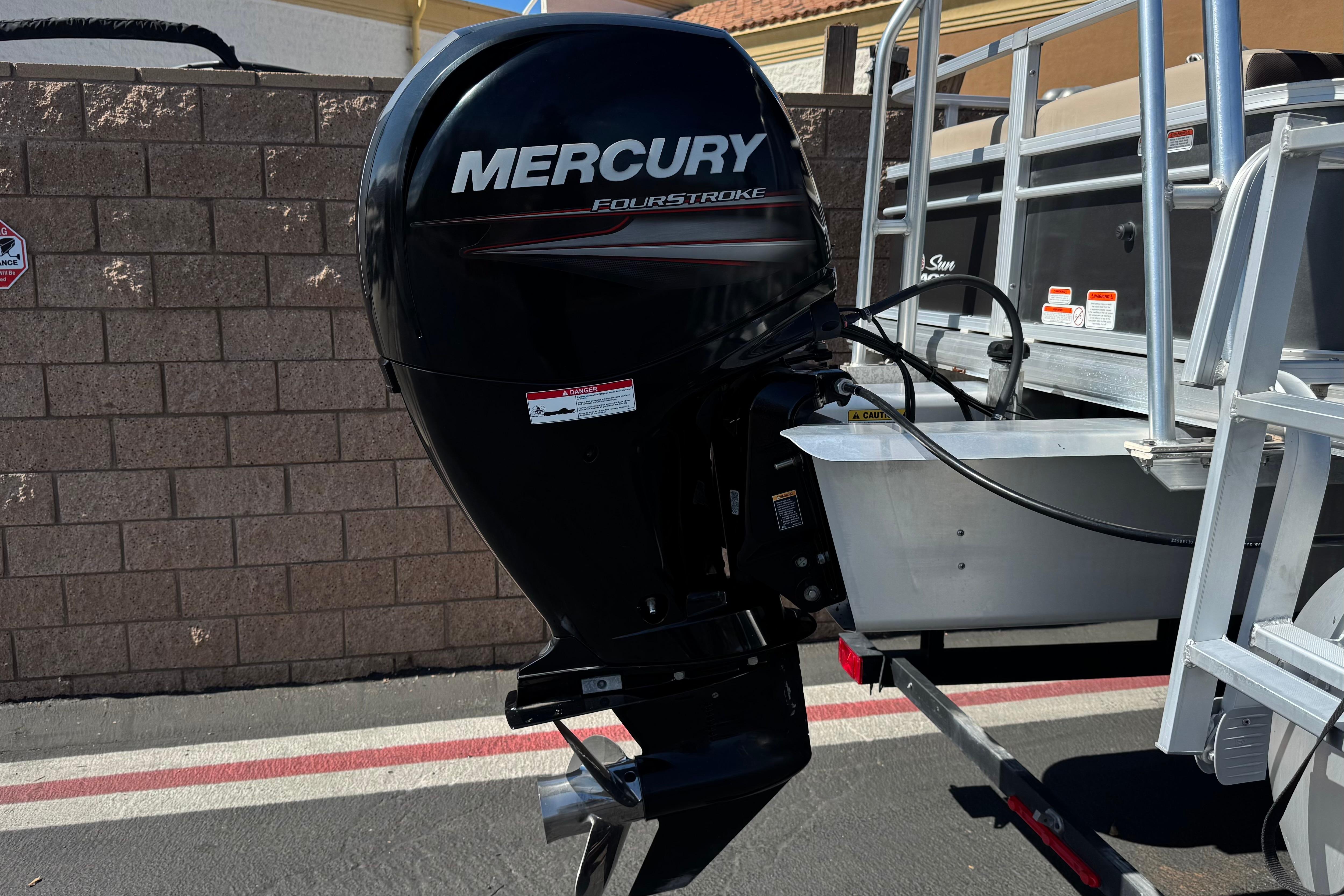 Mercury FourStroke engine on 2018 Sun Tracker SportFish 22 DLX boat, parked near brick wall.