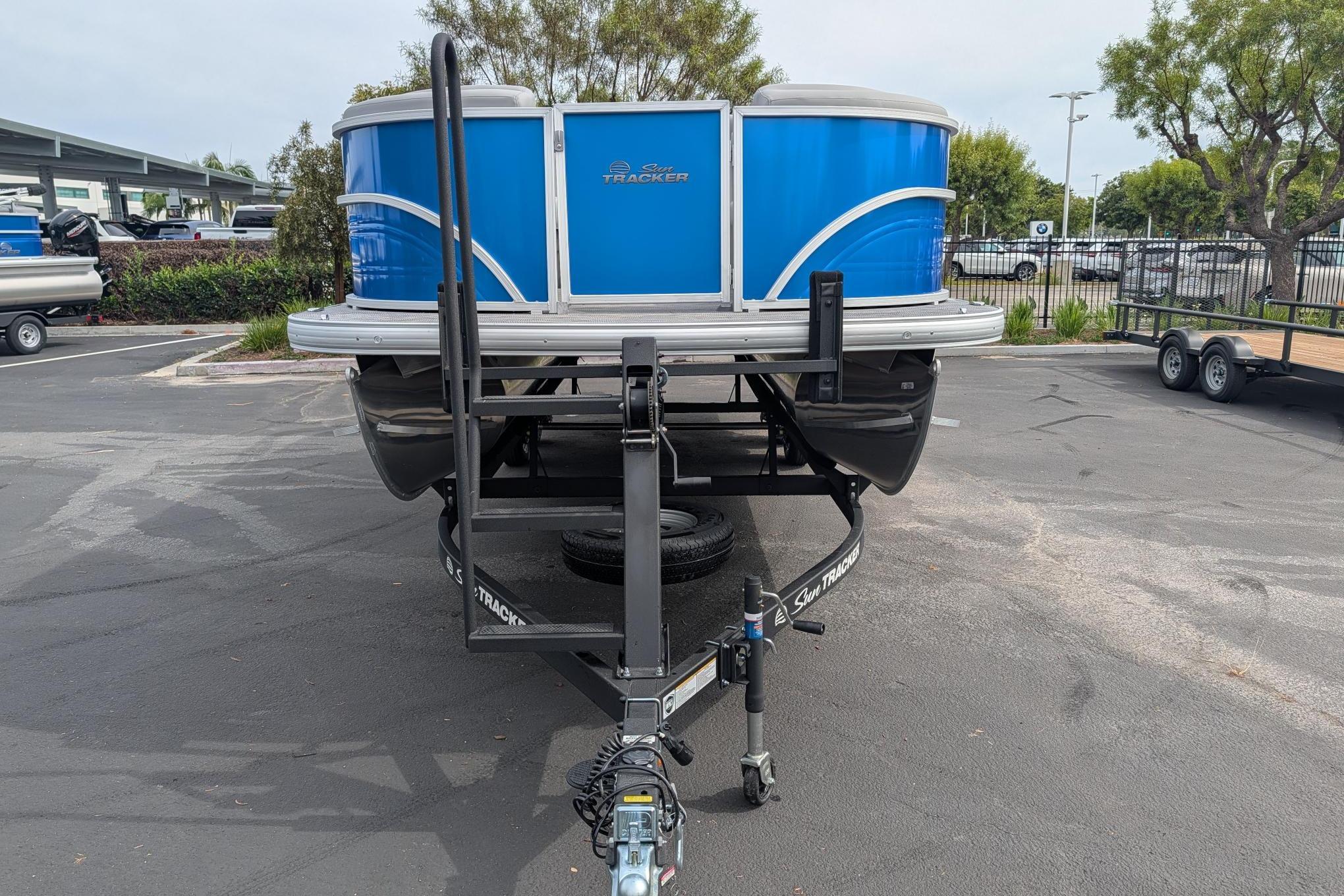 2026 Sun Tracker Party Barge 22 DLX pontoon boat on trailer in parking lot.