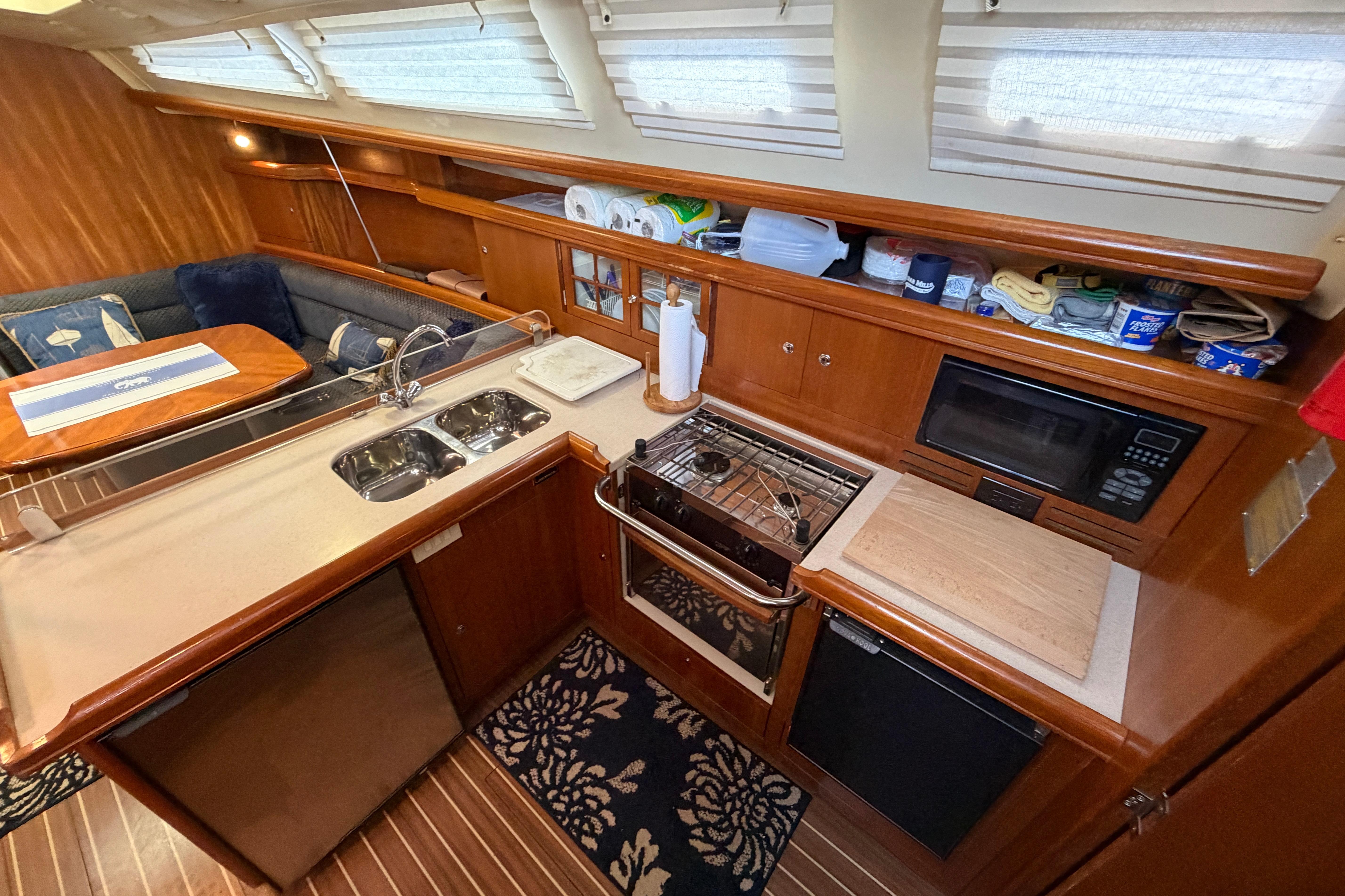 Interior of 2005 Hunter 38 sailboat kitchen with wood cabinetry and dining area.