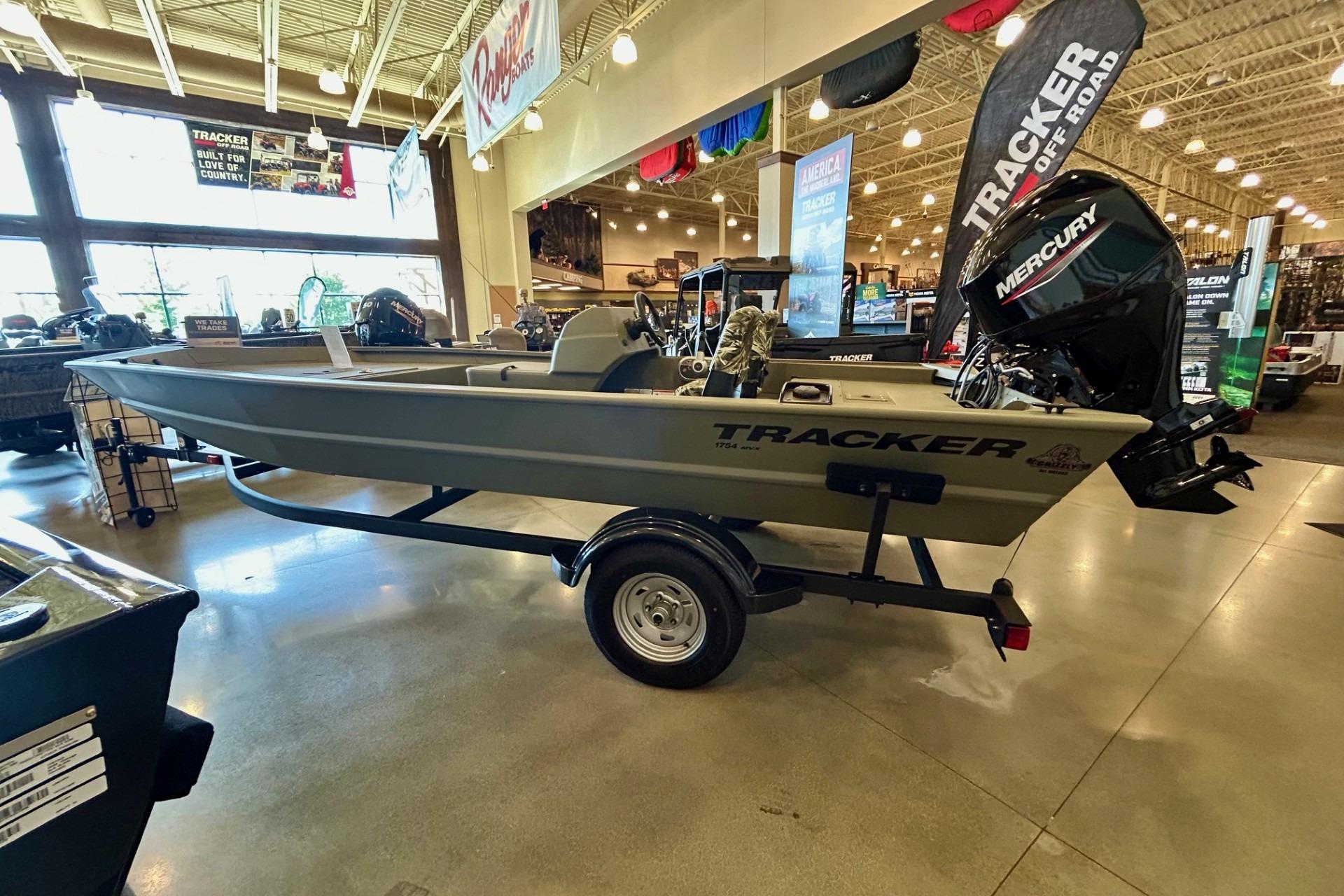 2026 Tracker Grizzly 1754 SC boat displayed indoors with Mercury engine.