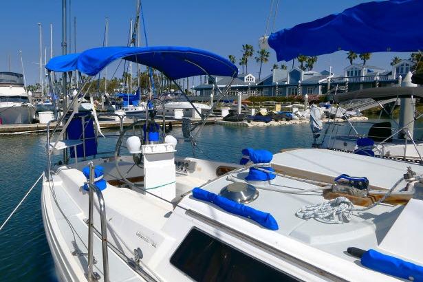 1989 Catalina 34 sailboat docked in a sunny marina with blue canopies.