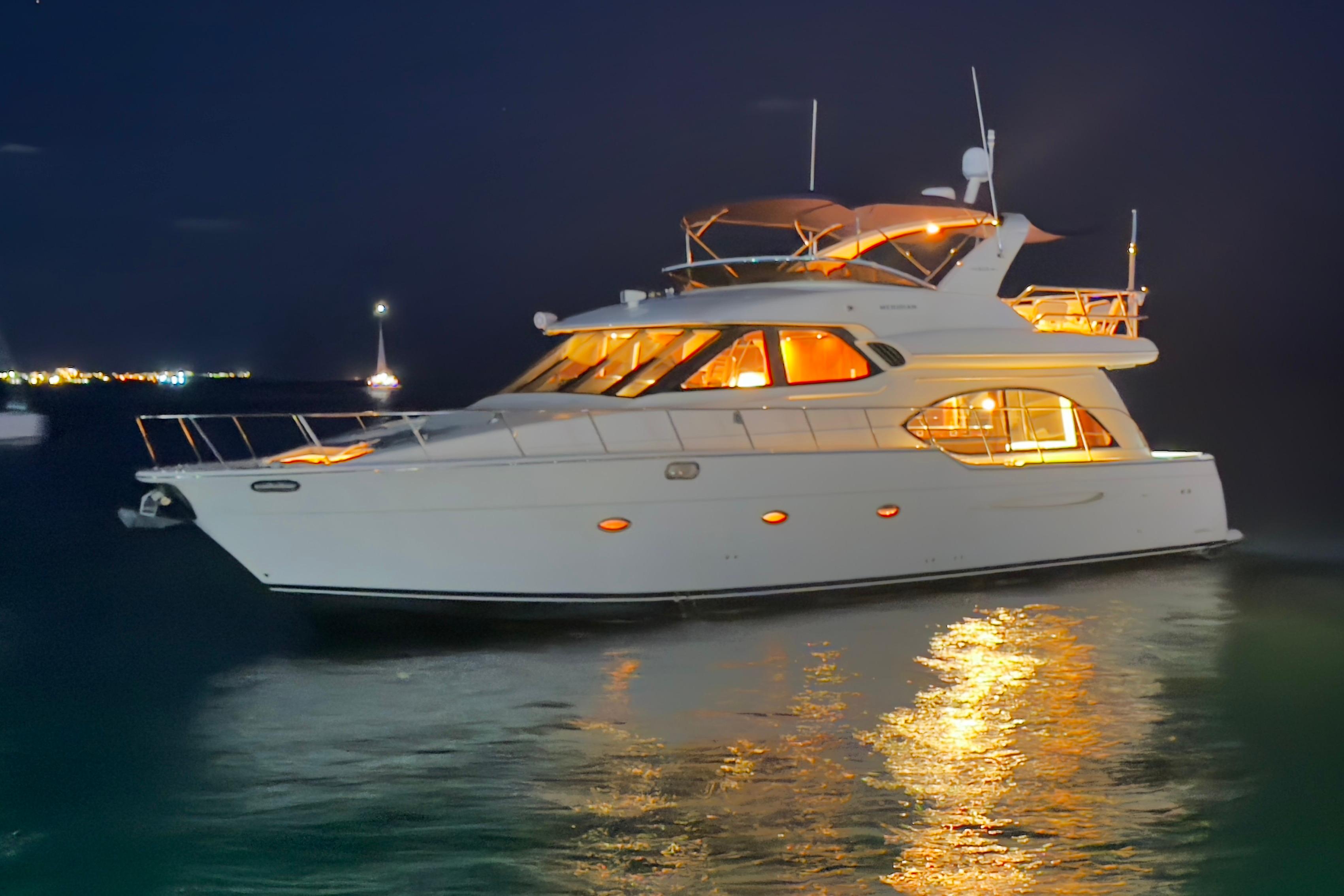 2008 Meridian 580 Pilothouse yacht illuminated at night on calm water.
