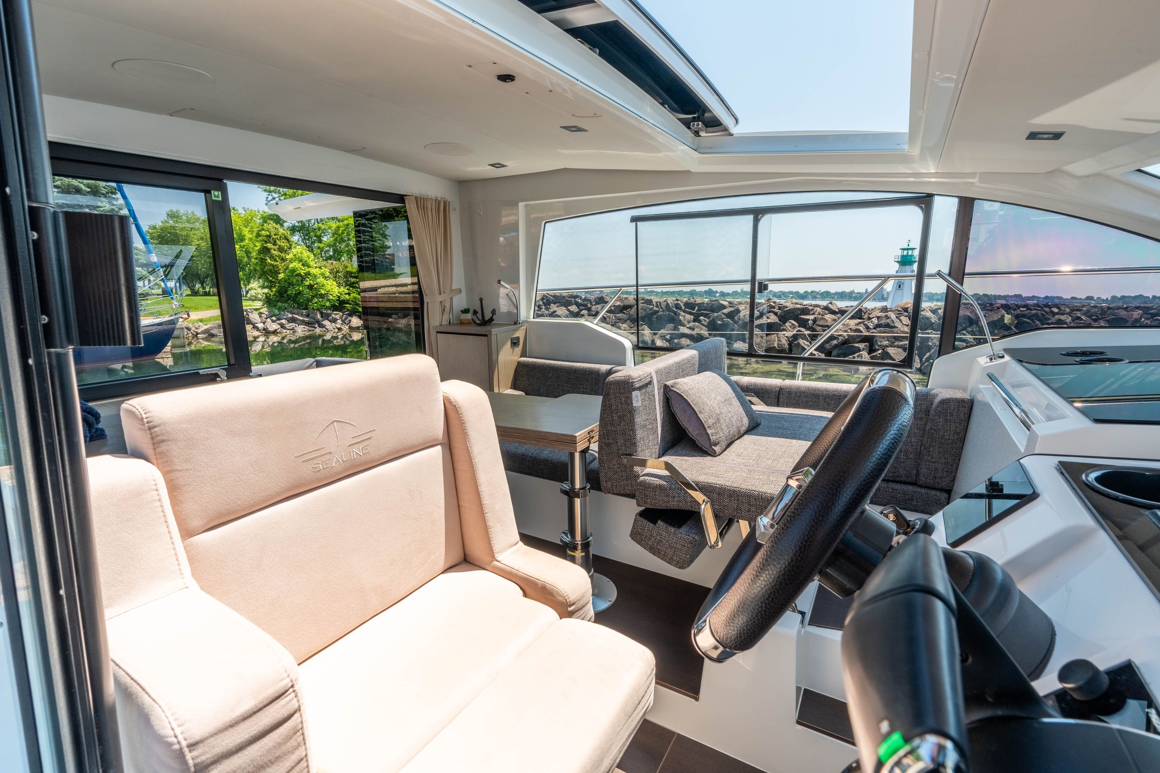 Interior view of a modern Sealine C335V yacht with comfortable seating and large windows.