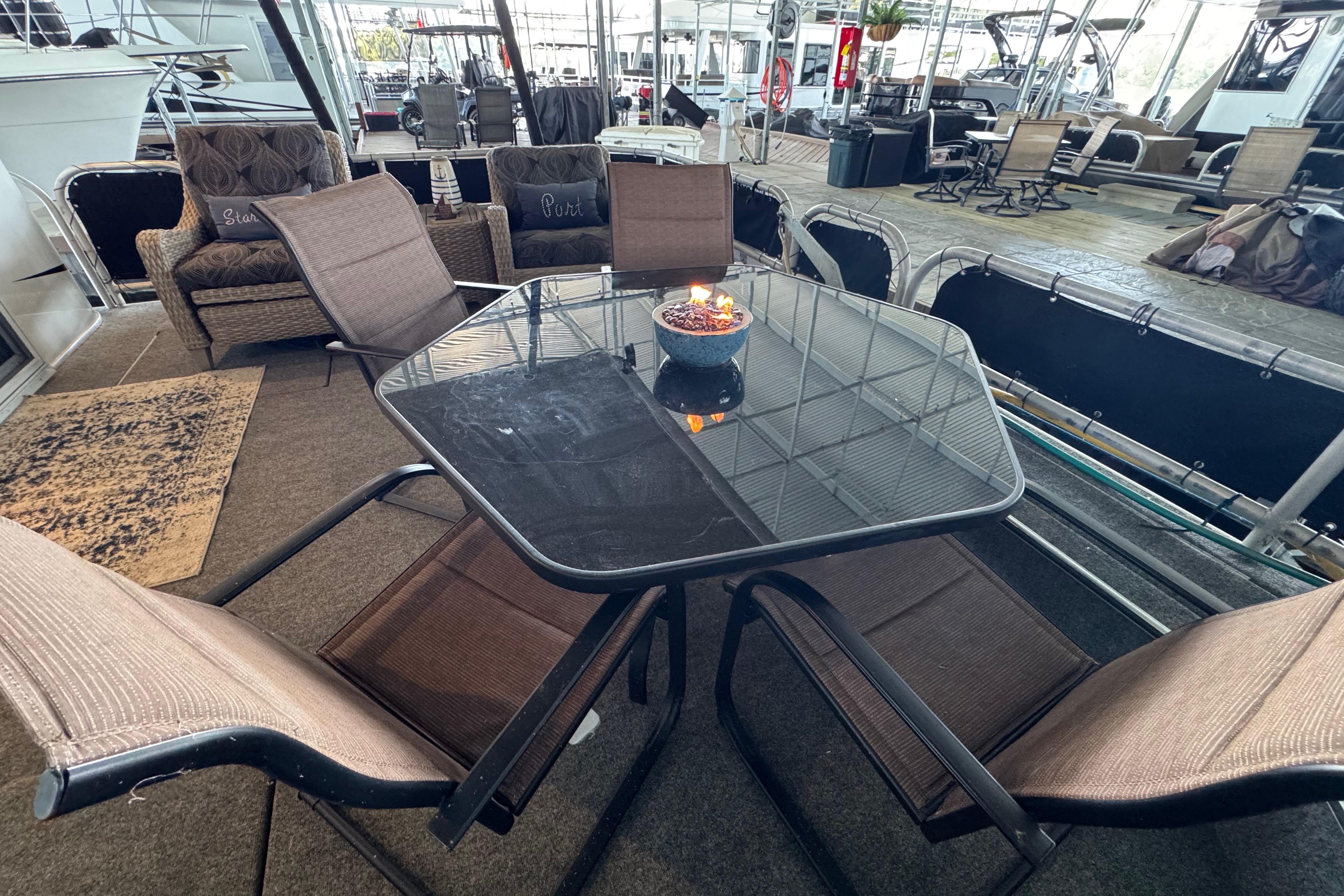 Outdoor seating area on a 2004 Starlite 65x16 houseboat with glass table and chairs.