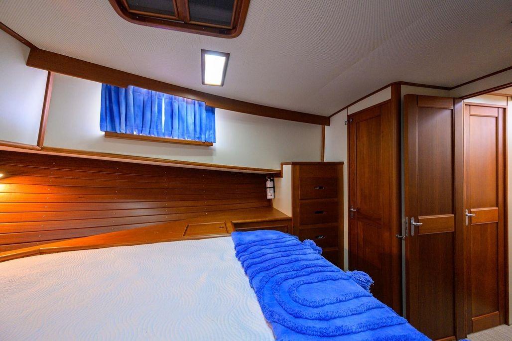 Cozy cabin interior of 1999 Grand Banks 42 Europa with wooden furnishings and blue accents.