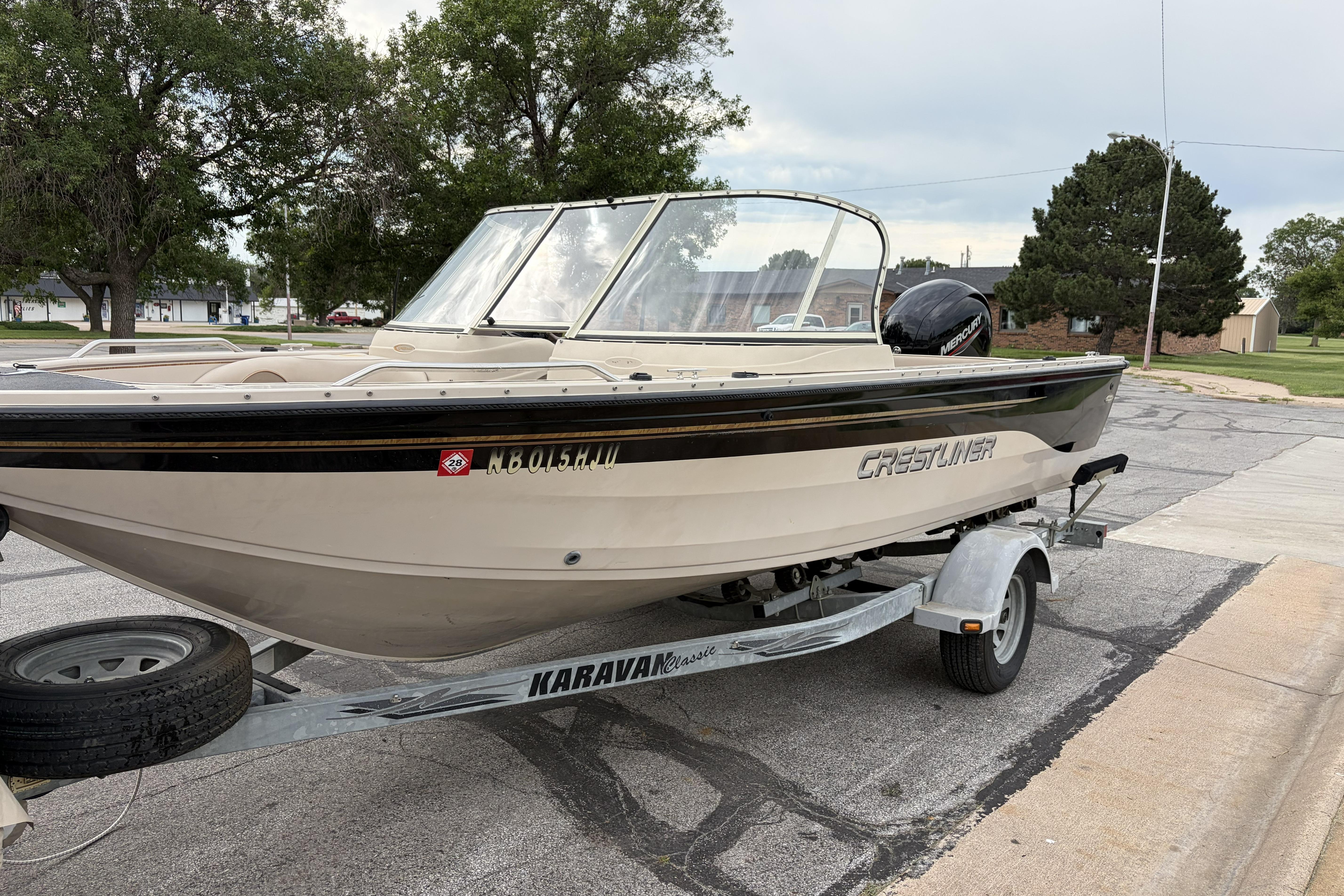 2002 Crestliner 1850 Sportfish boat on trailer, parked on street.